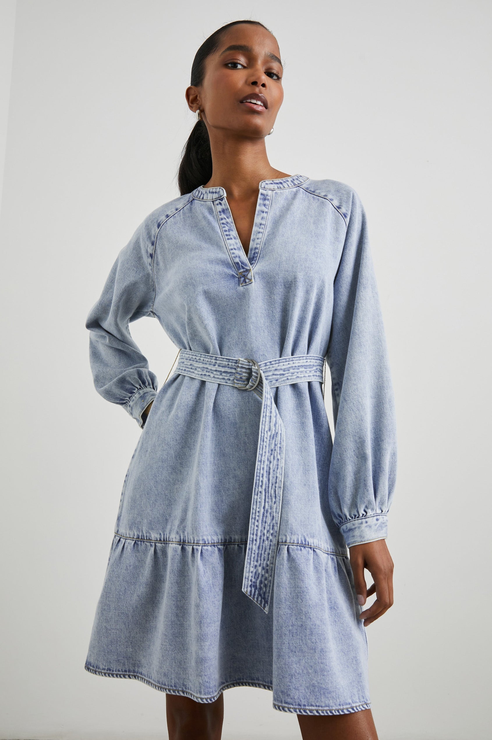 Lila Long-Sleeve Denim Mini Dress with a Fabric Double Ring Belt, a V Neck and Snap Cuffs in Faded Indigo Colorway - Front View Featured on Model 