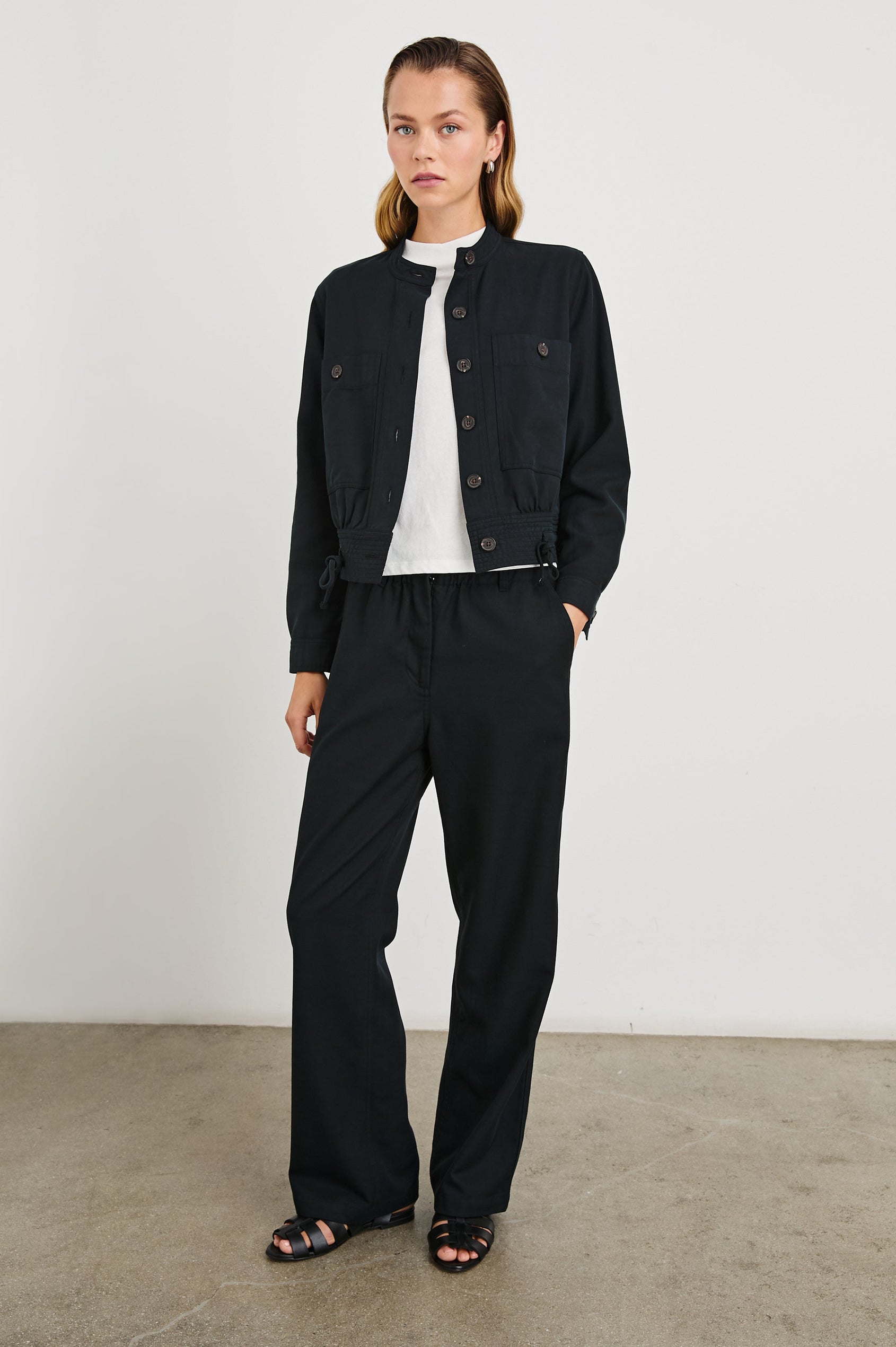 Lira Pants with a Paperbag Elastic Waist, Belt Loops, Two Front Pockets and Two Back Welt Pockets in Black Colorway - Front Full Body View Featured on Model 