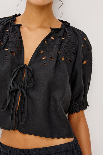 Lizbeth Milkmaid Top in Linen With Floral Eyelet Cutwork Plunging Tie-Front V-Neckline Front Ties Relaxed FIt Short Puff Sleeves in Black Ctolorway - Upper Body Front View Featured on Model