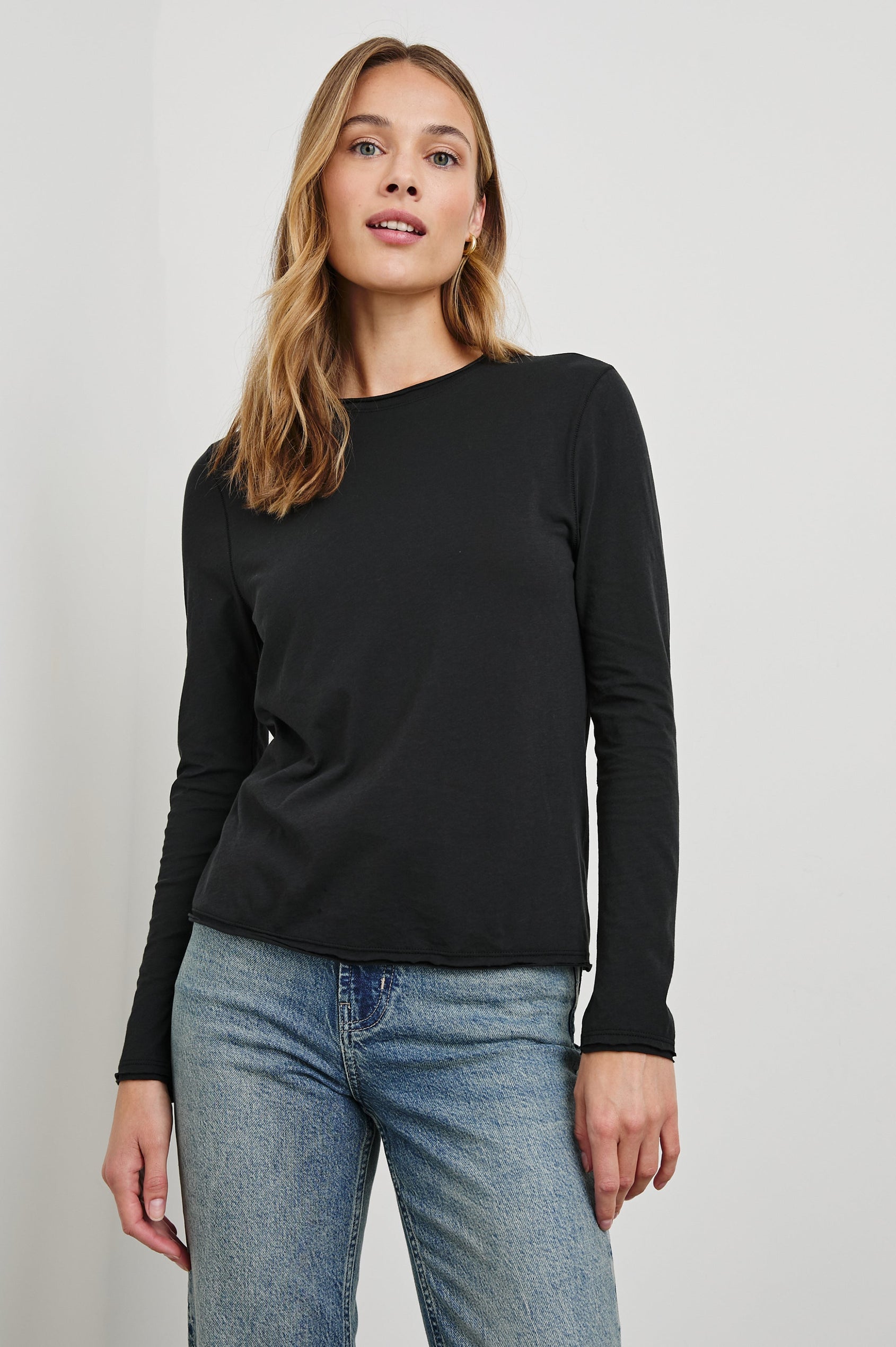 Long Sleeve Crew Neck T Shirt with Raw Hem, Collar and Cuffs in Black Colorway - Front View Featured on Model