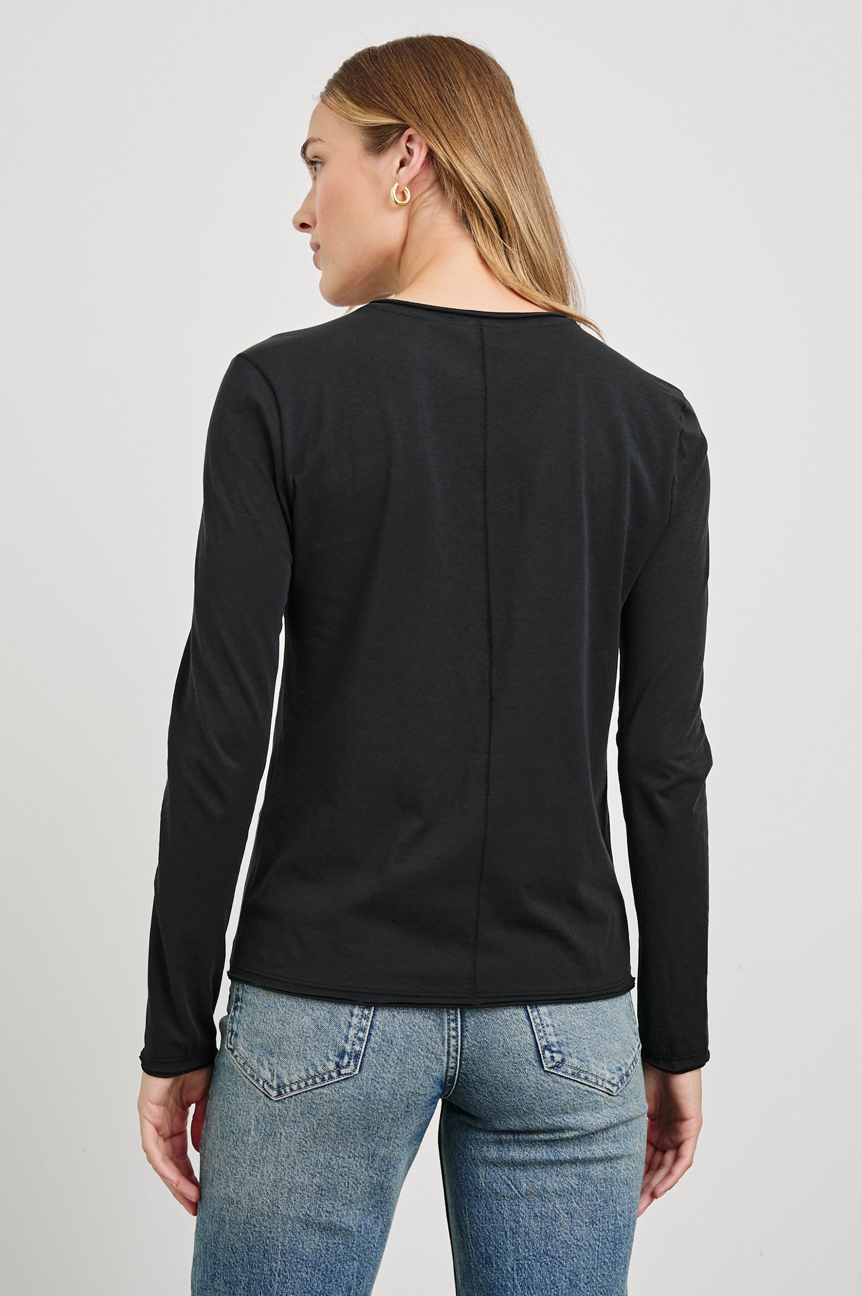 Long Sleeve Crew Neck T Shirt with Raw Hem, Collar and Cuffs in Black Colorway - Back View Featured on Model