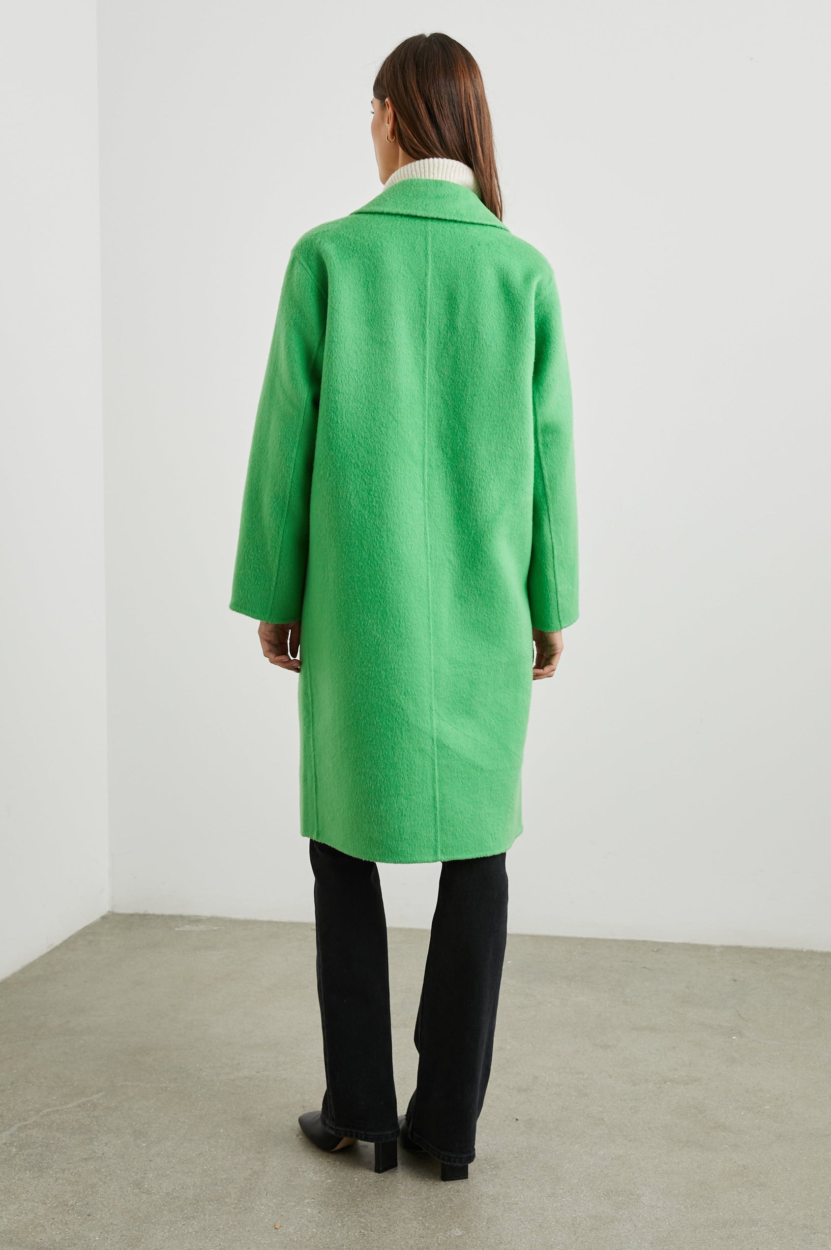 Lore Knee-Length Coat with Two Button Closure, Notched Lapels and Two Front Pockets in Green Apple Colorway - Back Full Body View Featured on Model