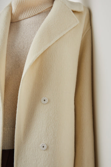 Lore Knee-Length Coat with Two Button Closure, Notched Lapels and Two Front Pockets in Ivory Colorway - Front View Featured on Model