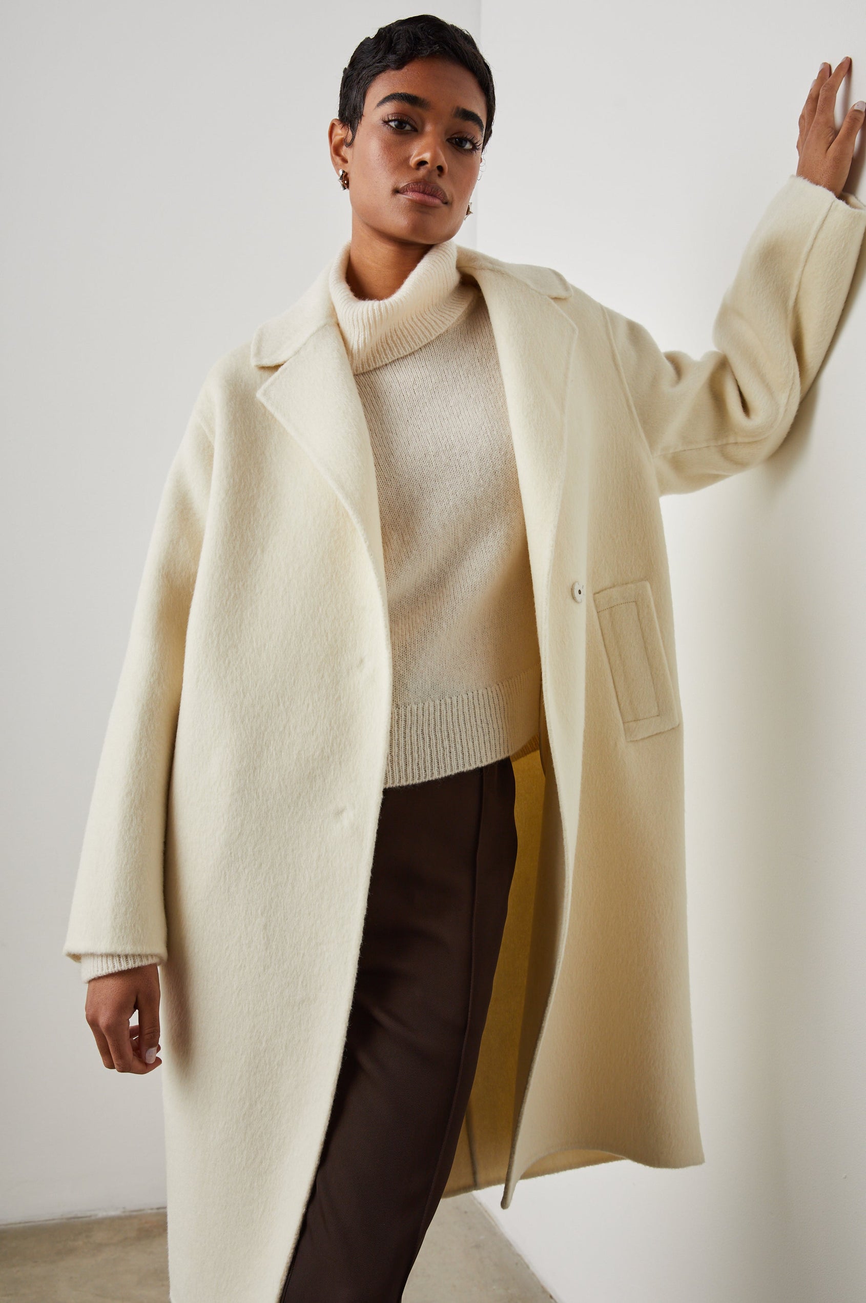 Lore Knee-Length Coat with Two Button Closure, Notched Lapels and Two Front Pockets in Ivory Colorway - Front View Featured on Model
