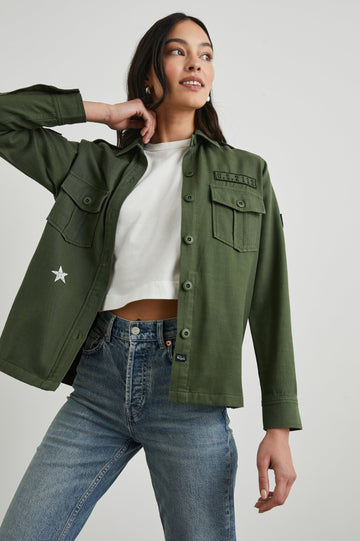 Loren Long-Sleeve Shirt Jacket with Button Closure, Two Chest Button Flap Pockets, a Military Patch on Each Arm, a Military Number above One Chest Pocket, and Button Shoulder Tabs in Military Olive Colorway, with White Stars - Front View Featured on Model
