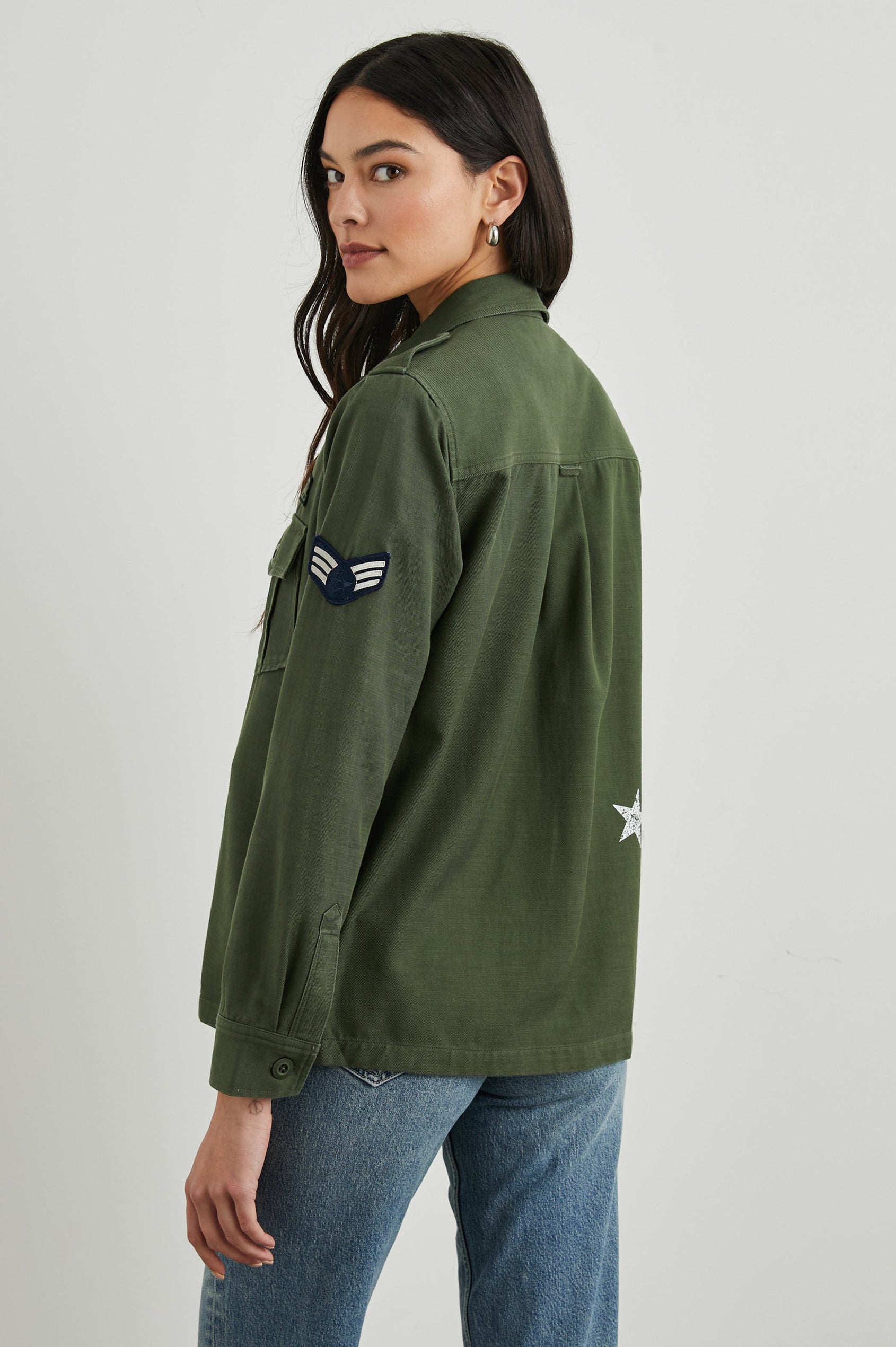 Loren Long-Sleeve Shirt Jacket with Button Closure, Two Chest Button Flap Pockets, a Military Patch on Each Arm, a Military Number above One Chest Pocket, and Button Shoulder Tabs in Military Olive Colorway, with White Stars - Back View Featured on Model