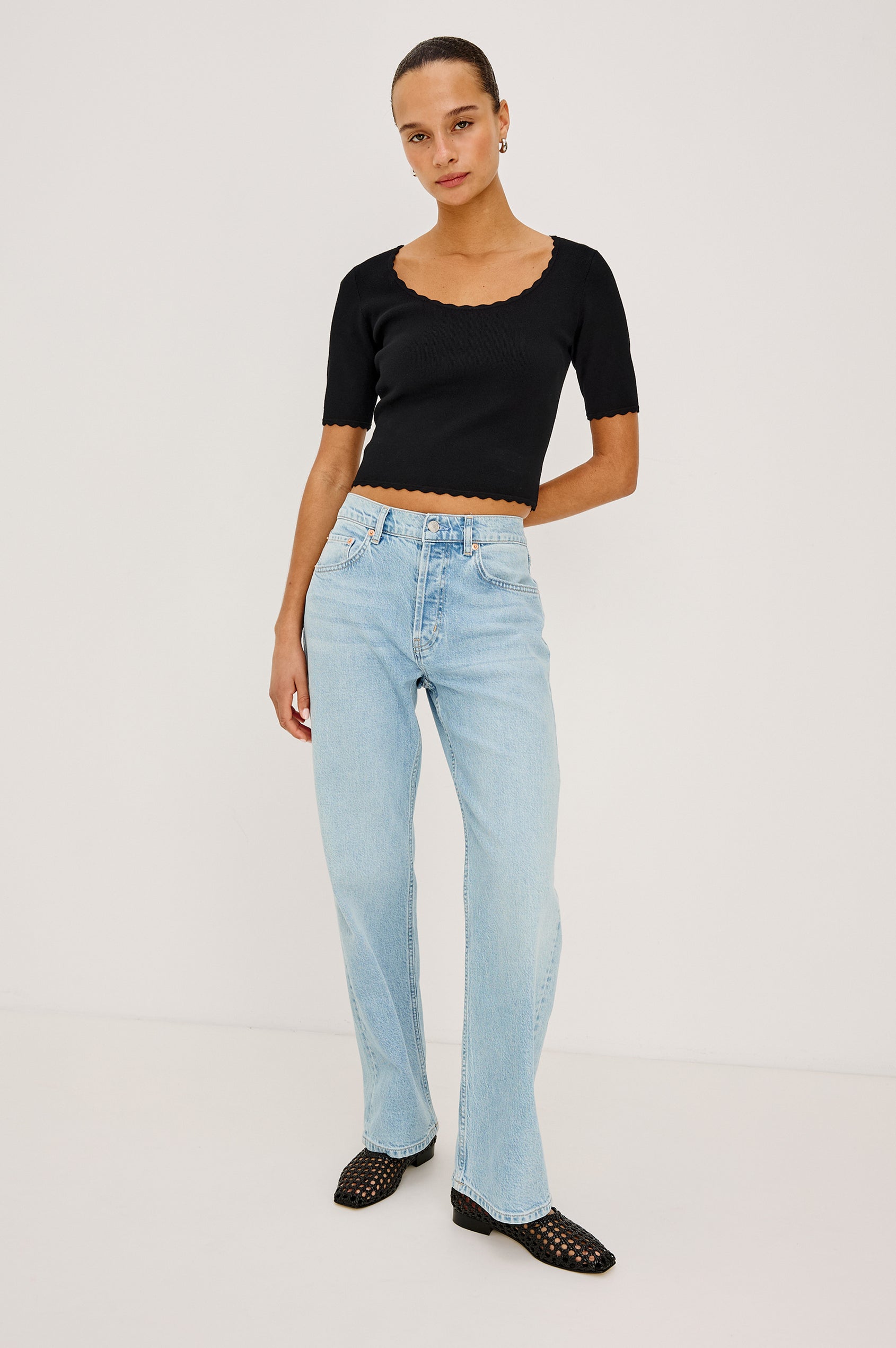 Louanna Fitted Cropped Top in Compact Knit With Scallop-Trimmed Scoop Neckline, Short Sleeves, and Hem in Black Colorway - Full Body Front View Featured on Model