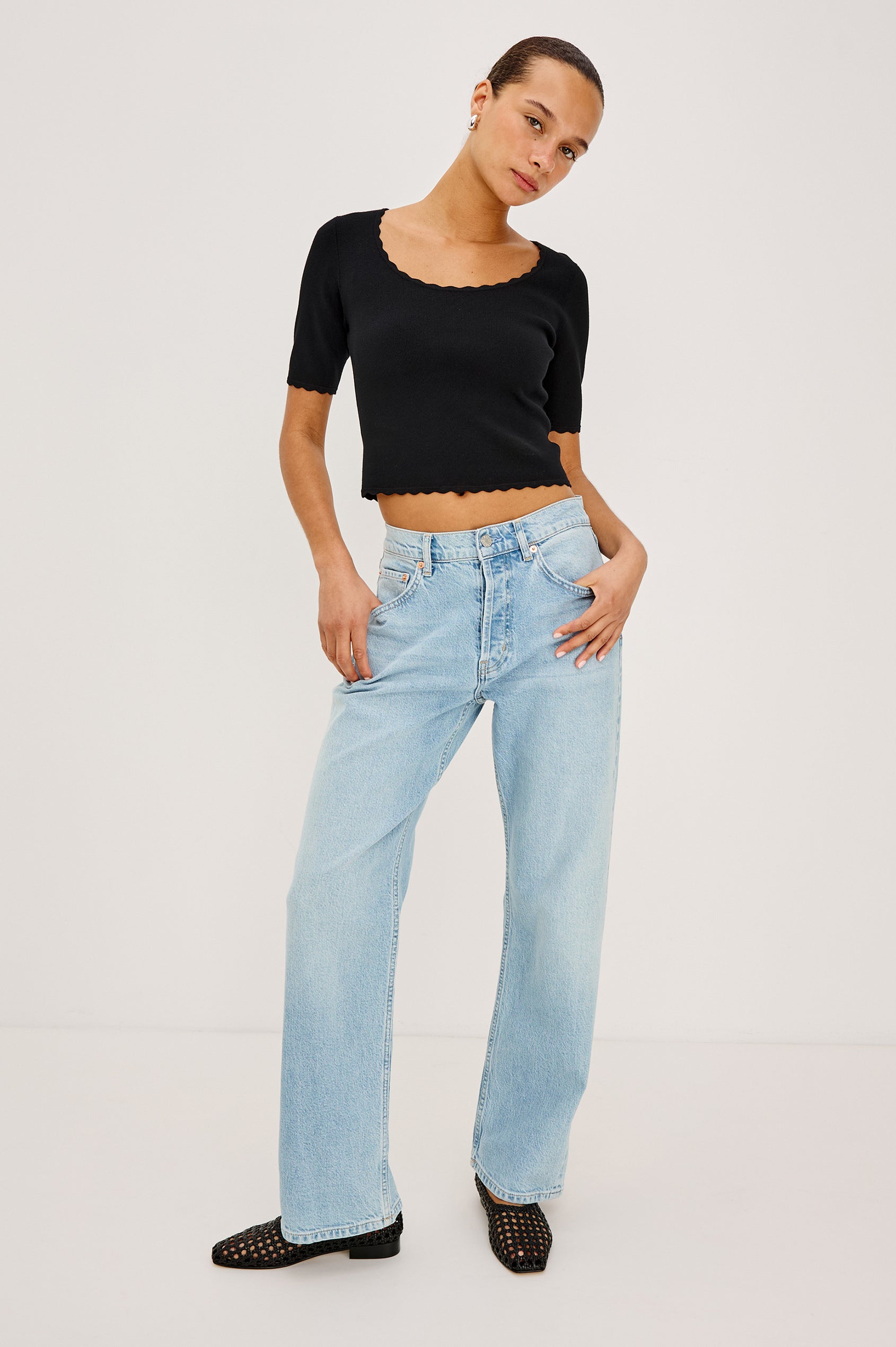 Louanna Fitted Cropped Top in Compact Knit With Scallop-Trimmed Scoop Neckline, Short Sleeves, and Hem in Black Colorway - Full Body Front View Featured on Model
