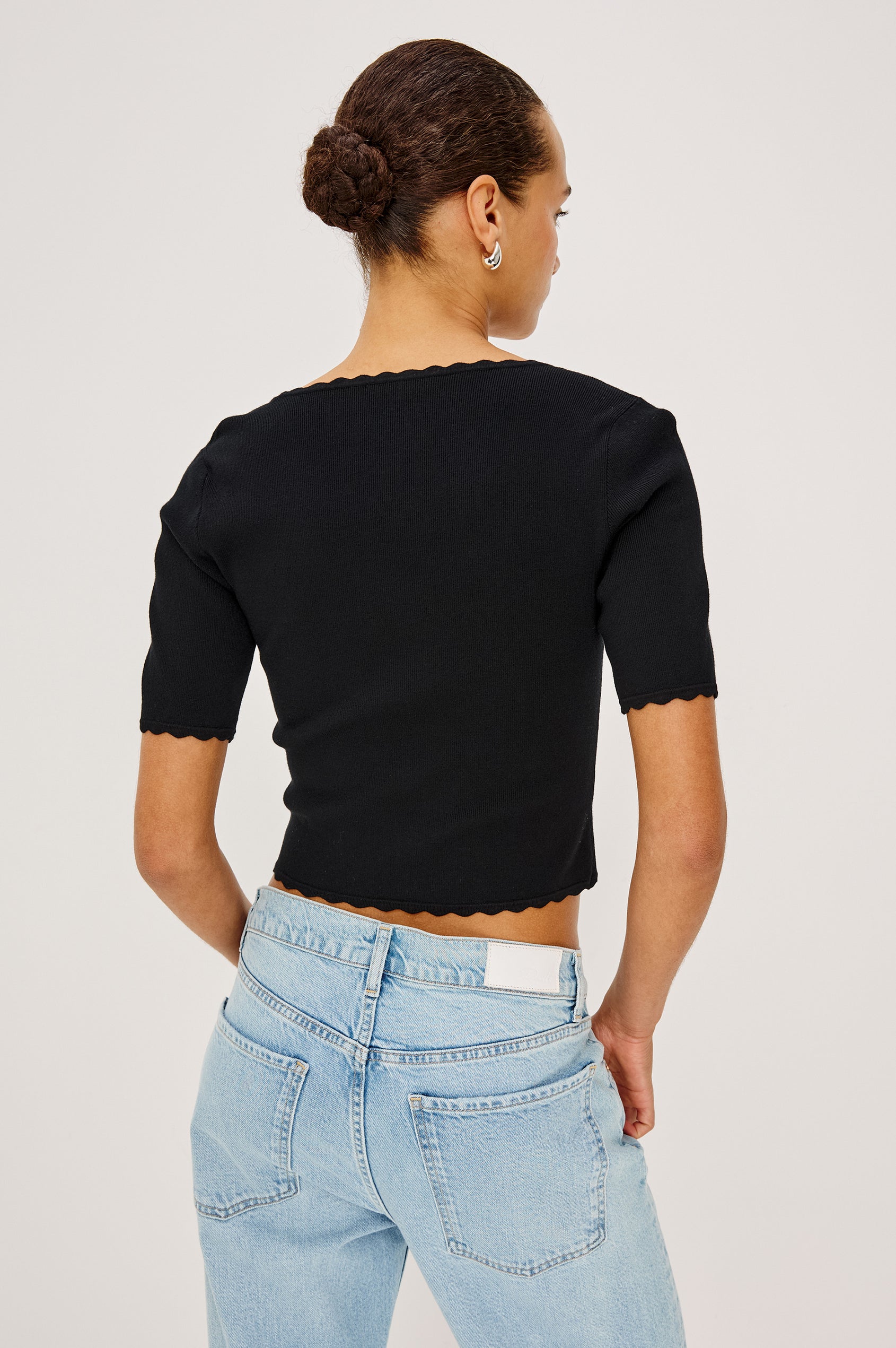 Louanna Fitted Cropped Top in Compact Knit With Scallop-Trimmed Scoop Neckline, Short Sleeves, and Hem in Black Colorway - Upper Body Back View Featured on Model
