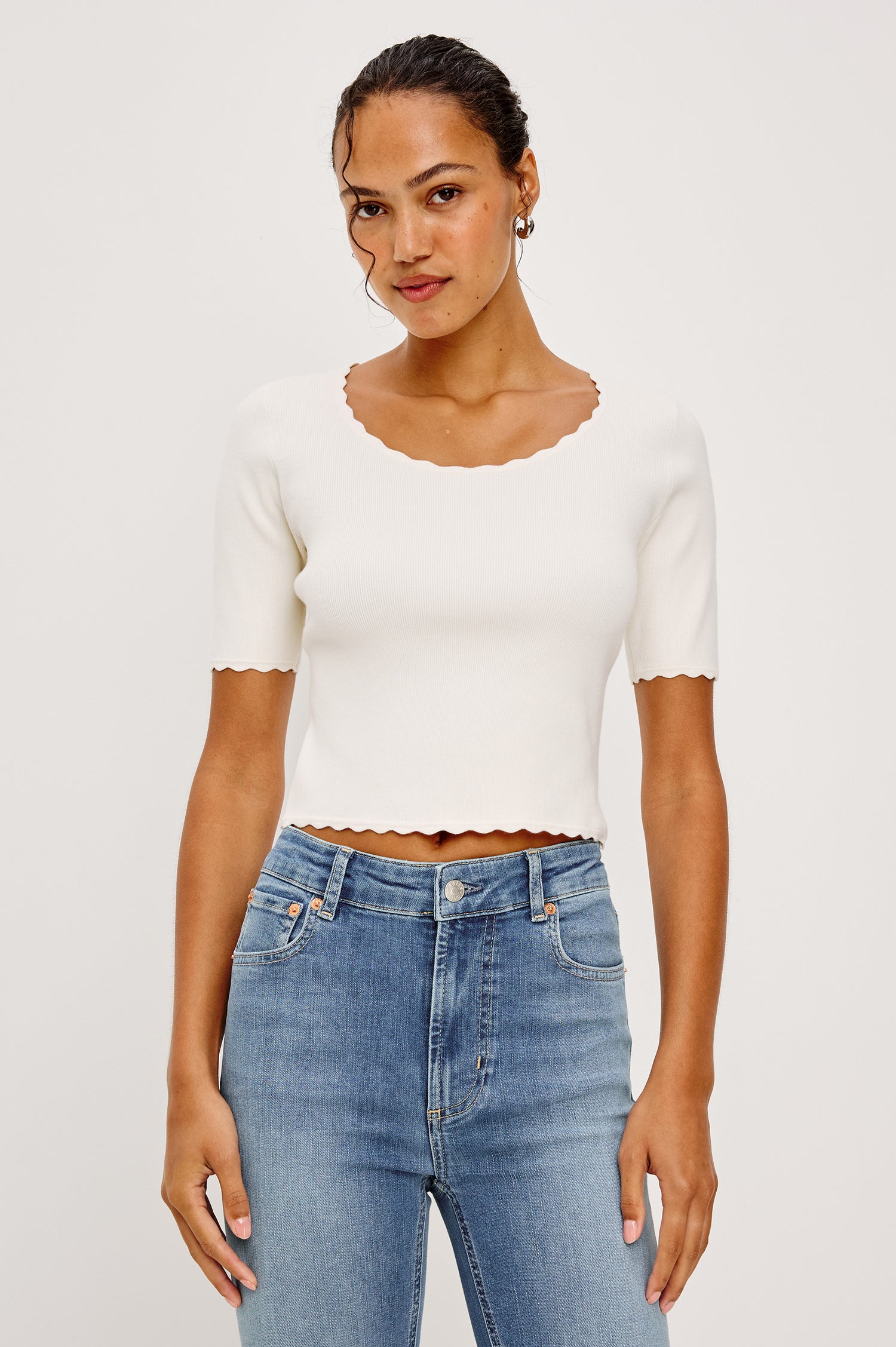 Louanna Fitted Cropped Top in Compact Knit With Scallop-Trimmed Scoop Neckline Short Sleeves and Hem in Ivory Colorway - Upper Body Front View Featured on Model