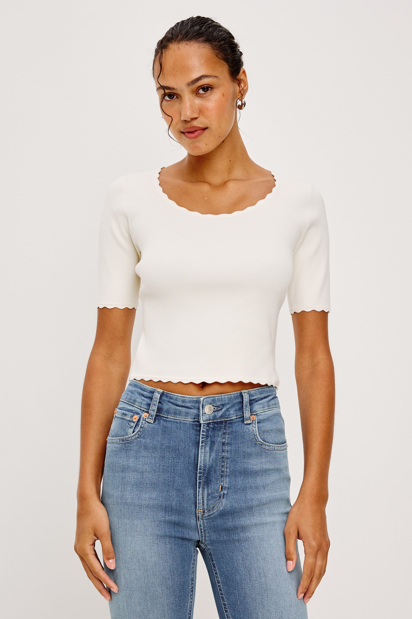 Louanna Fitted Cropped Top in Compact Knit With Scallop-Trimmed Scoop Neckline Short Sleeves and Hem in Ivory Colorway - Upper Body Front View Featured on Model