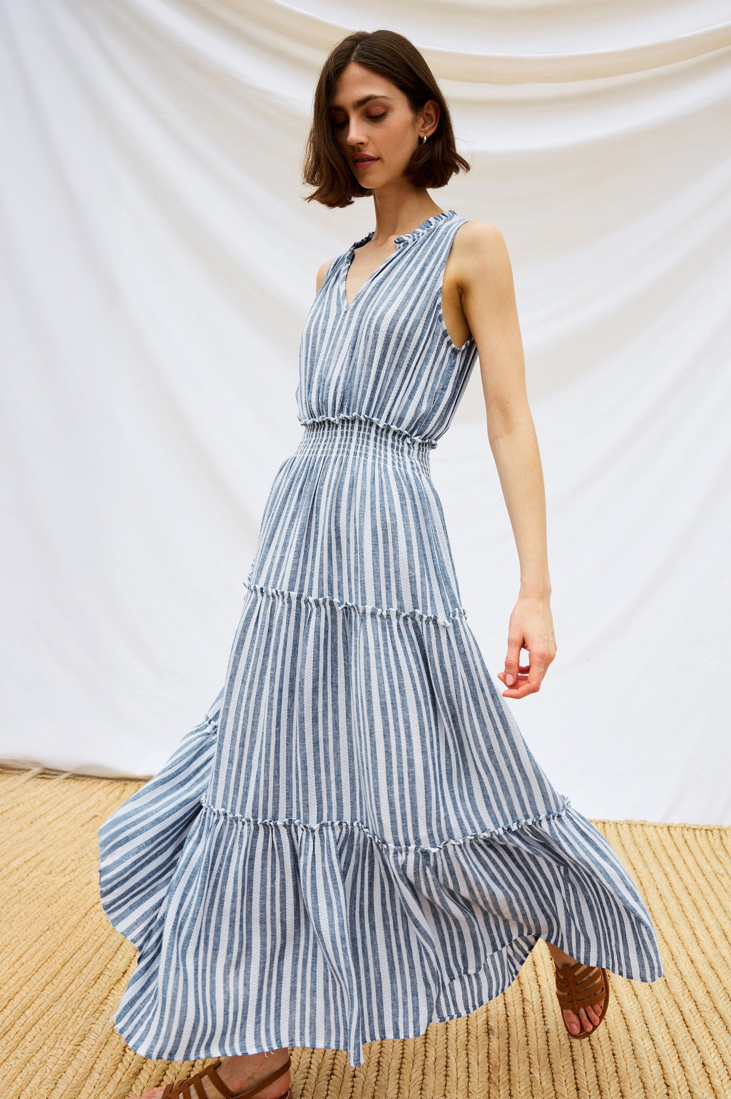 Loulou V-Neck Midi Dress with Smocked Elastic Waistband and a Multi Tiered Skirt in Blue/White Jalisco Stripe Colorway. Stylized Full Body Front View Shown on Model.