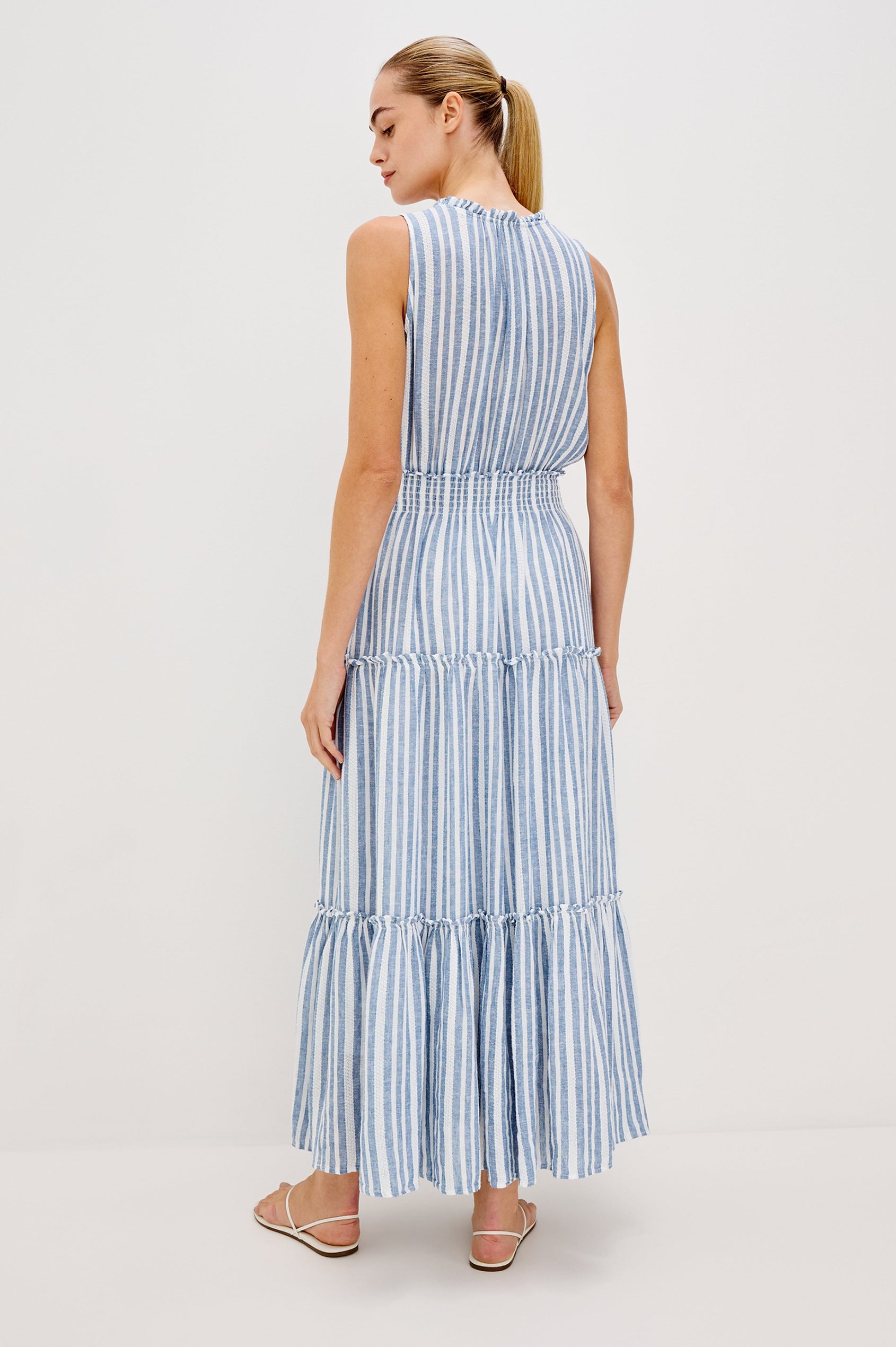 Loulou V-Neck Midi Dress with Smocked Elastic Waistband and a Multi Tiered Skirt in Blue/White Jalisco Stripe Colorway. Full Body Back View Shown on Model.