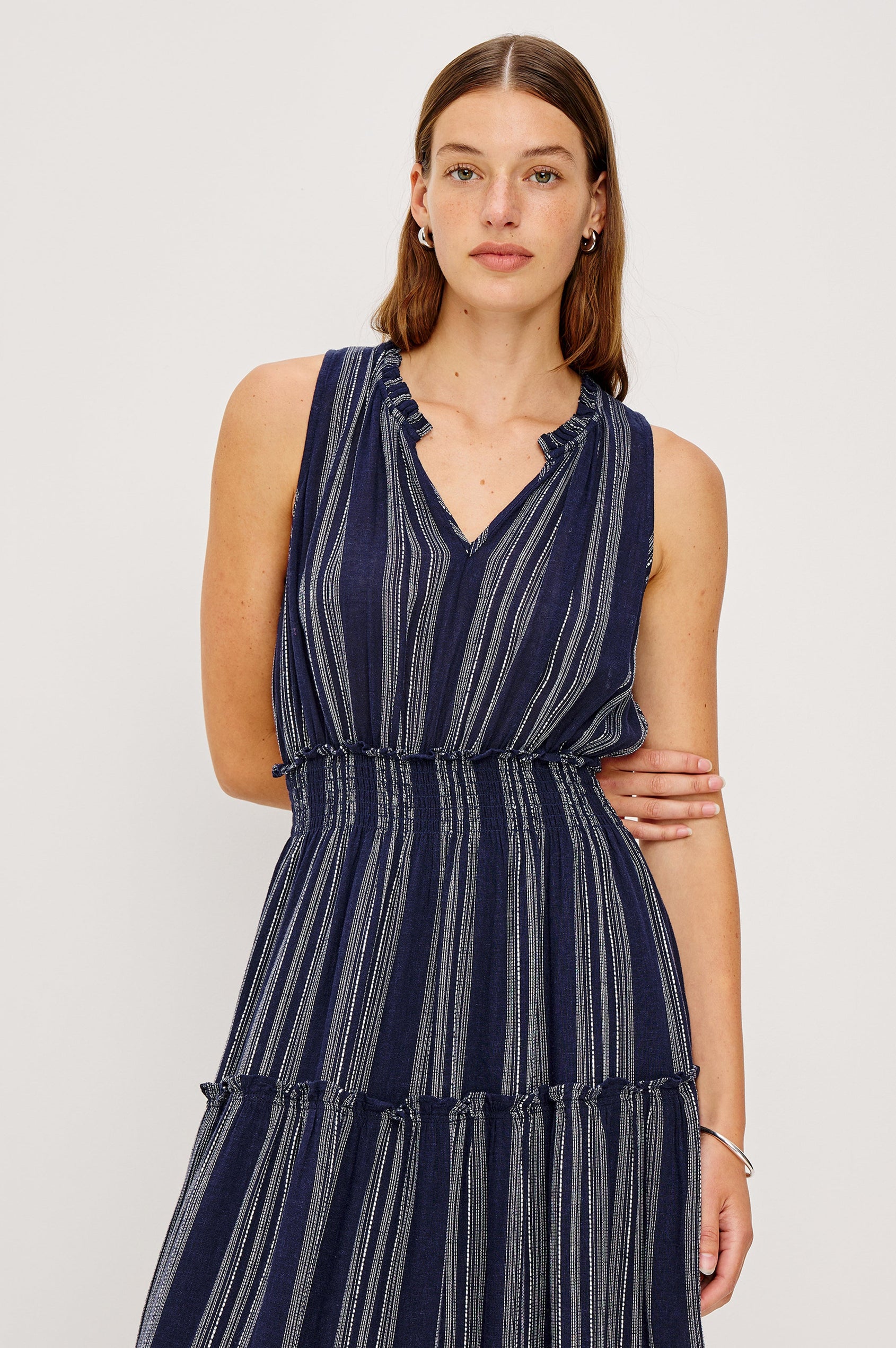 Loulou V-Neck Midi Dress with Smocked Elastic Waistband and a Multi Tiered Skirt in navy blue Magalia Stripe Colorway. Close up of Details on model