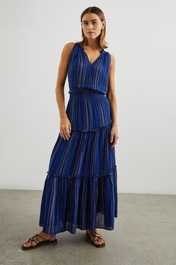 Loulou Sleeveless Midi Dress with a V Neck, Shirred Collar, Smocked Waist and Tiered Skirt in Nola Stripe Colorway, Thin White Vertical Stripes on dark blue - Front Full Body View Featured on Model