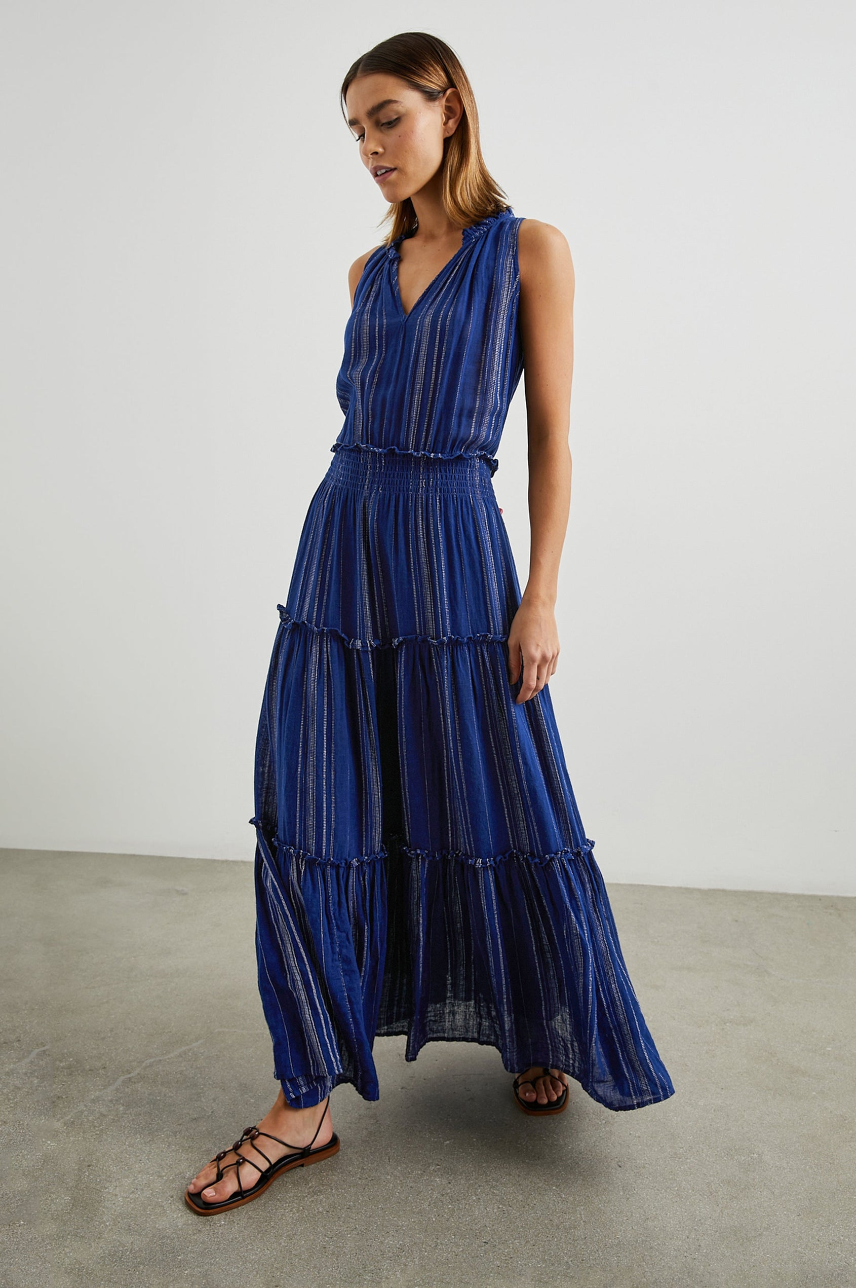 Loulou Sleeveless Midi Dress with a V Neck, Shirred Collar, Smocked Waist and Tiered Skirt in Nola Stripe Colorway, Thin White Vertical Stripes on dark blue - Front Full Body View Featured on Model