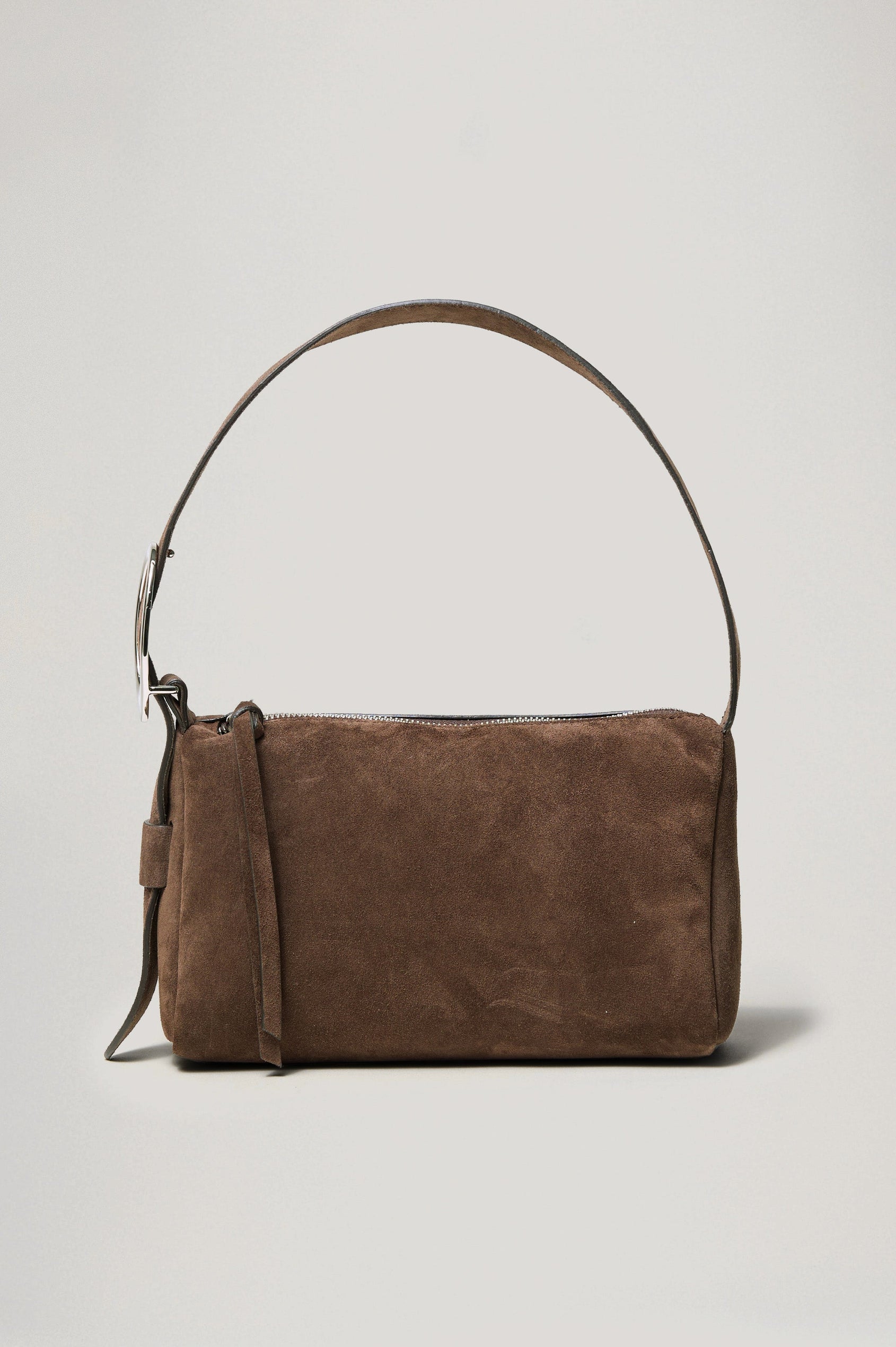 The Lucca is a smooth suede shoulder bag with an adjustable strap and polished silver oval buckle. In Espresso Suede colorway. Front view featured.