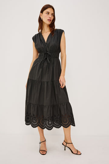 Lucia Midi Dress with Cap Sleeves, a Crossover V neckline, an Elastic Waist with Ties, and a Tiered Skirt in black Colorway - Front Full Body View Featured on Model