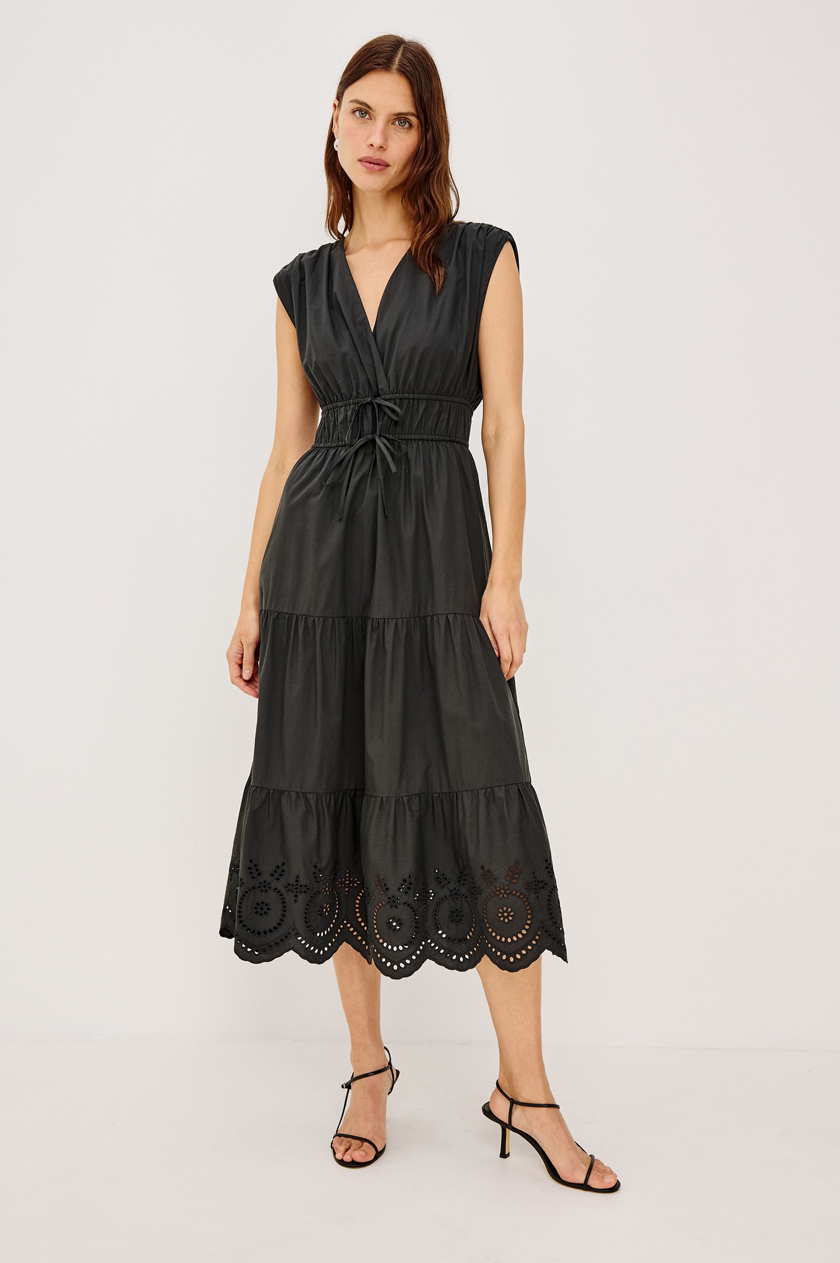 Lucia Midi Dress with Cap Sleeves, a Crossover V neckline, an Elastic Waist with Ties, and a Tiered Skirt in black Colorway - Front Full Body View Featured on Model