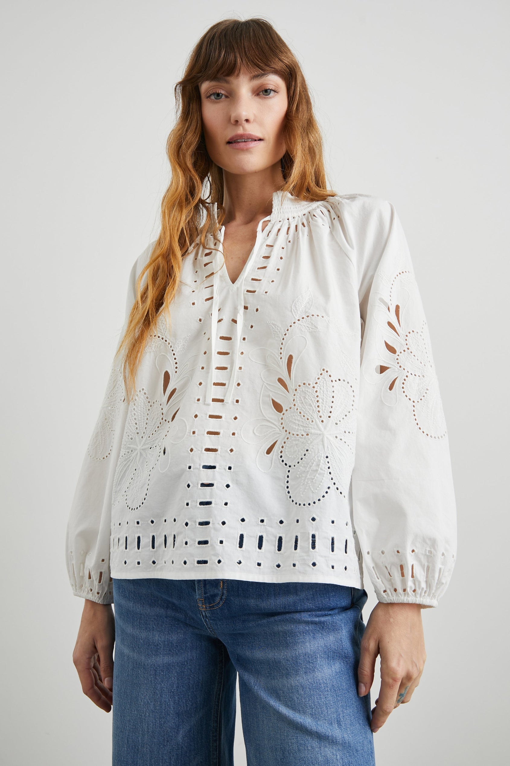 Lucinda Long-Sleeve Top with Billowy Sleeves, a V Neck with a Drawstring Collar, and a Floral and Geometric Eyelet Design in White Colorway - Front View Featured on Model  