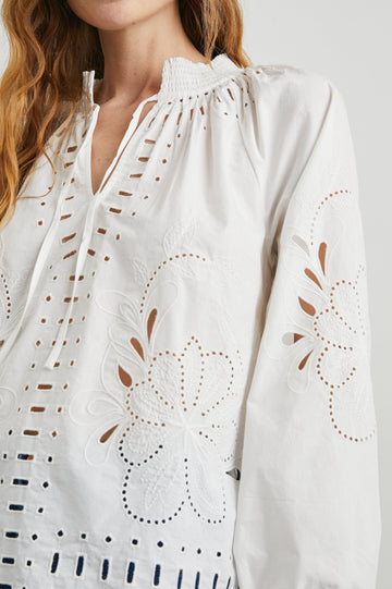Lucinda Long-Sleeve Top with Billowy Sleeves, a V Neck with a Drawstring Collar, and a Floral and Geometric Eyelet Design in White Colorway - Front View Featured on Model  
