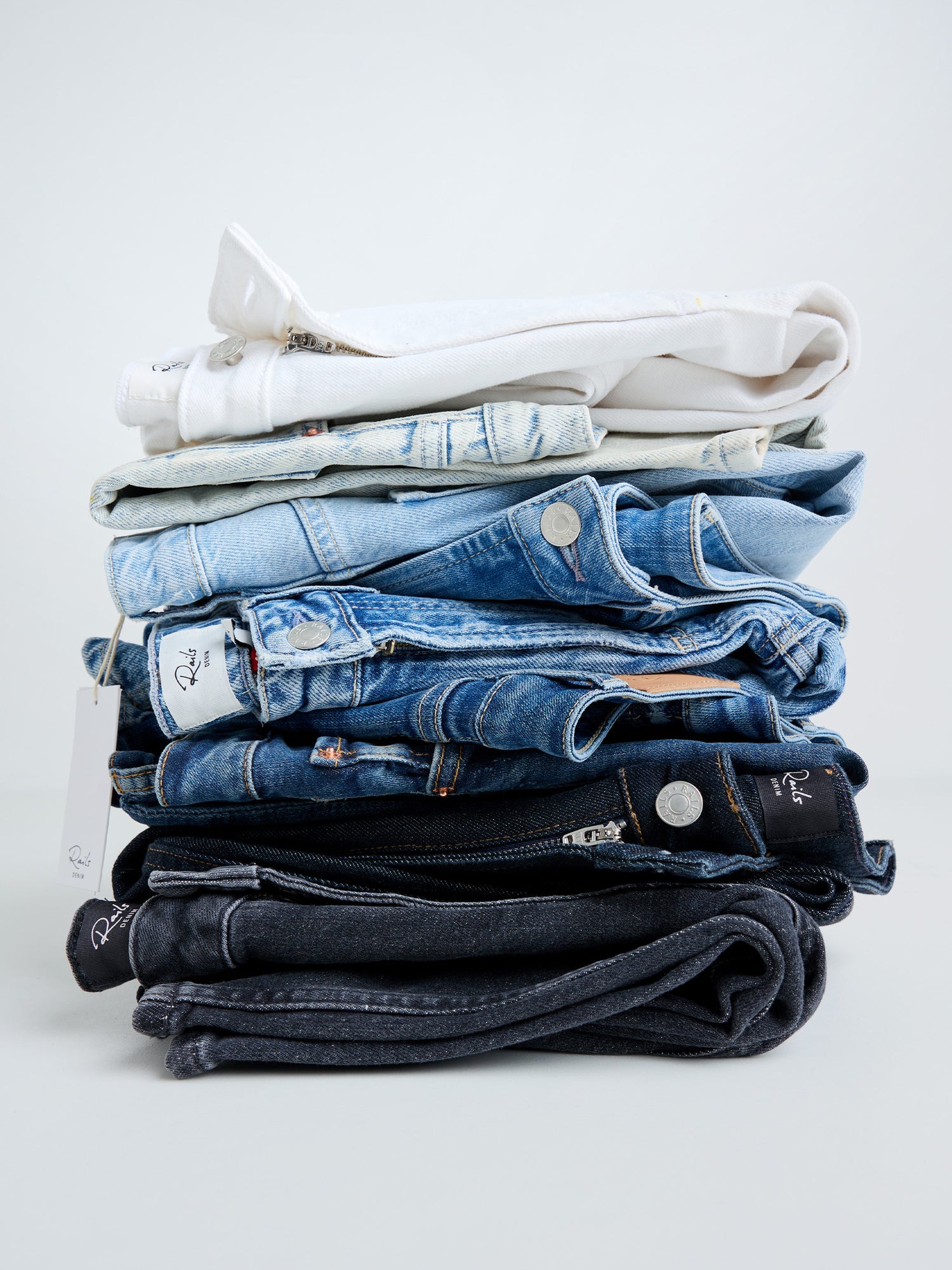 Stack of folded jeans on a light gray background