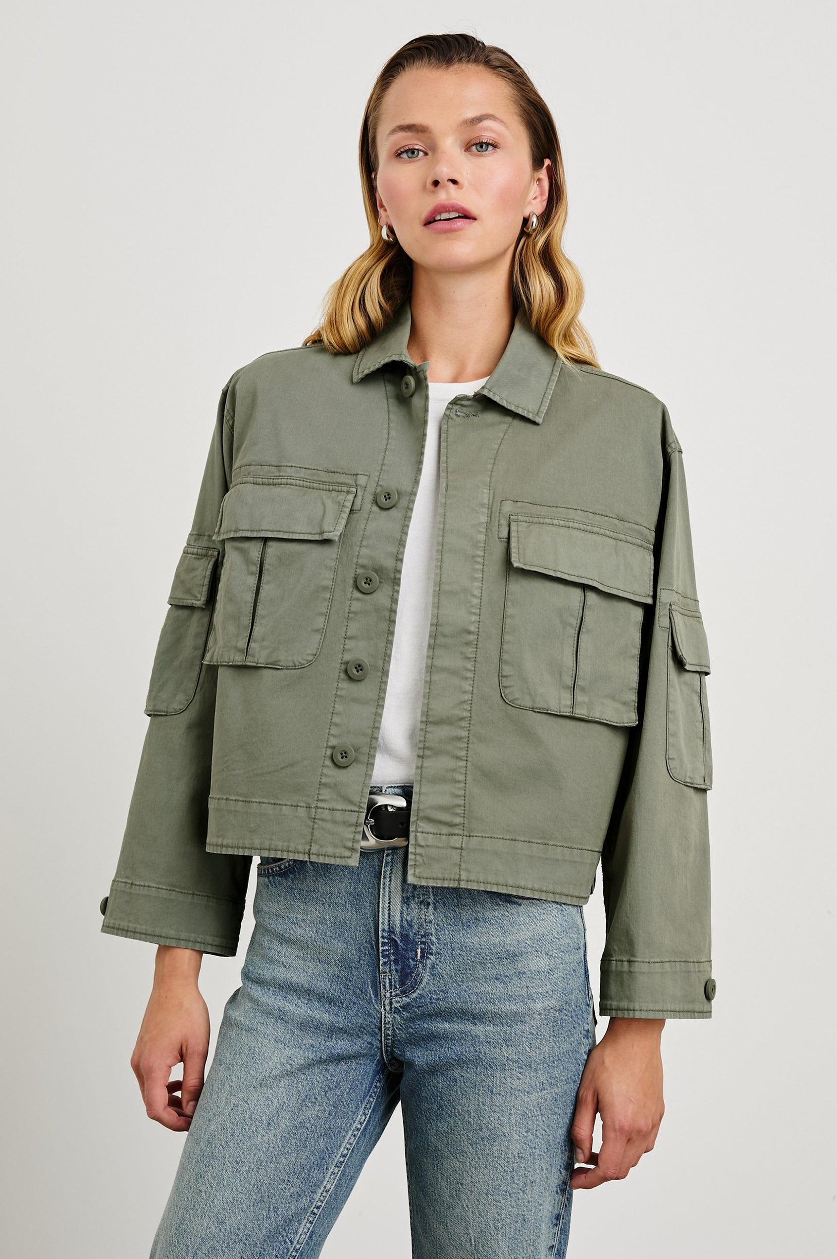 Madison Jacket with Button Closure, Two Chest Flap Pockets, Two Sleeve Flap Pockets, Adjustable Button Tab at Cuffs, and a Button Tab at Hem in Dark Olive Colorway - Front View Featured on Model  