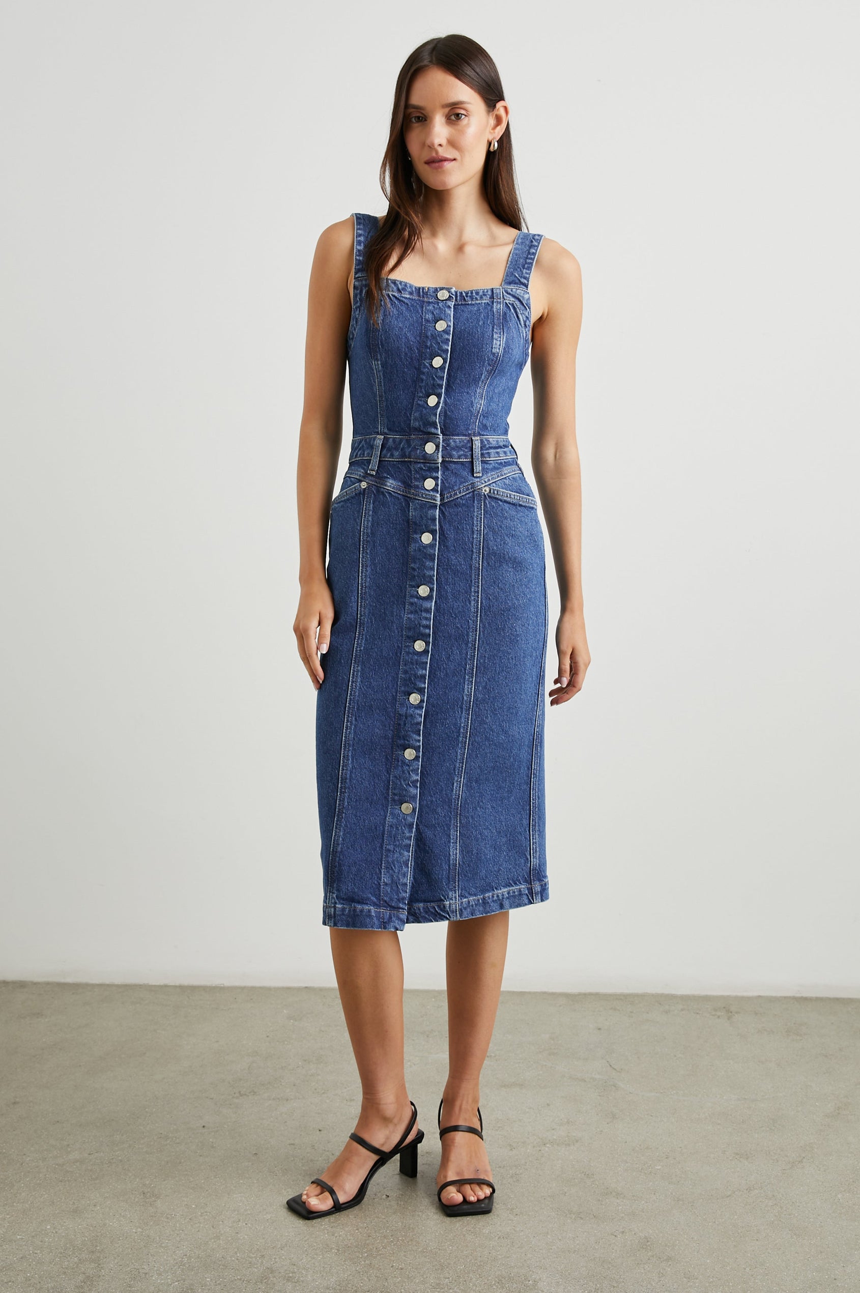 Malibu Sleeveless Denim Midi Dress with Shoulder Straps, Buttons Down the Front, a Square Neckline in the Front and Back, Two Front Pockets and Two Back Patch Pockets in Mazarine Colorway - Front Full Body View Featured on Model