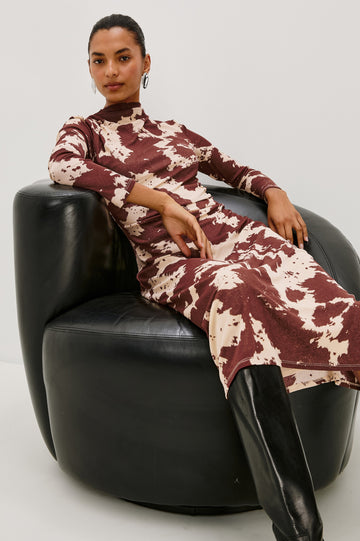 Margaret Long-Sleeve Midi Dress with a Mock Neck and Shirring along the Left Side in Cowgirl Colorway - Stylized Front View Featured on Model Sitting in Leather Chair