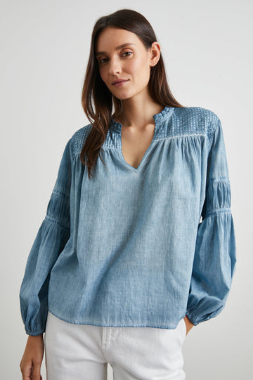 Marli Long-Sleeve Top with a V Neck, Ruffle Collar, Ruching on the Sleeves and Yoke Seam, Tiered Sleeves, and Pleats on the Yoke in Faded Blue Colorway - Front View Featured on Model 