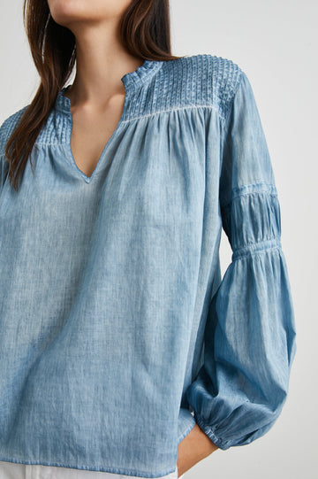 Marli Long-Sleeve Top with a V Neck, Ruffle Collar, Ruching on the Sleeves and Yoke Seam, Tiered Sleeves, and Pleats on the Yoke in Faded Blue Colorway - Front View Featured on Model 