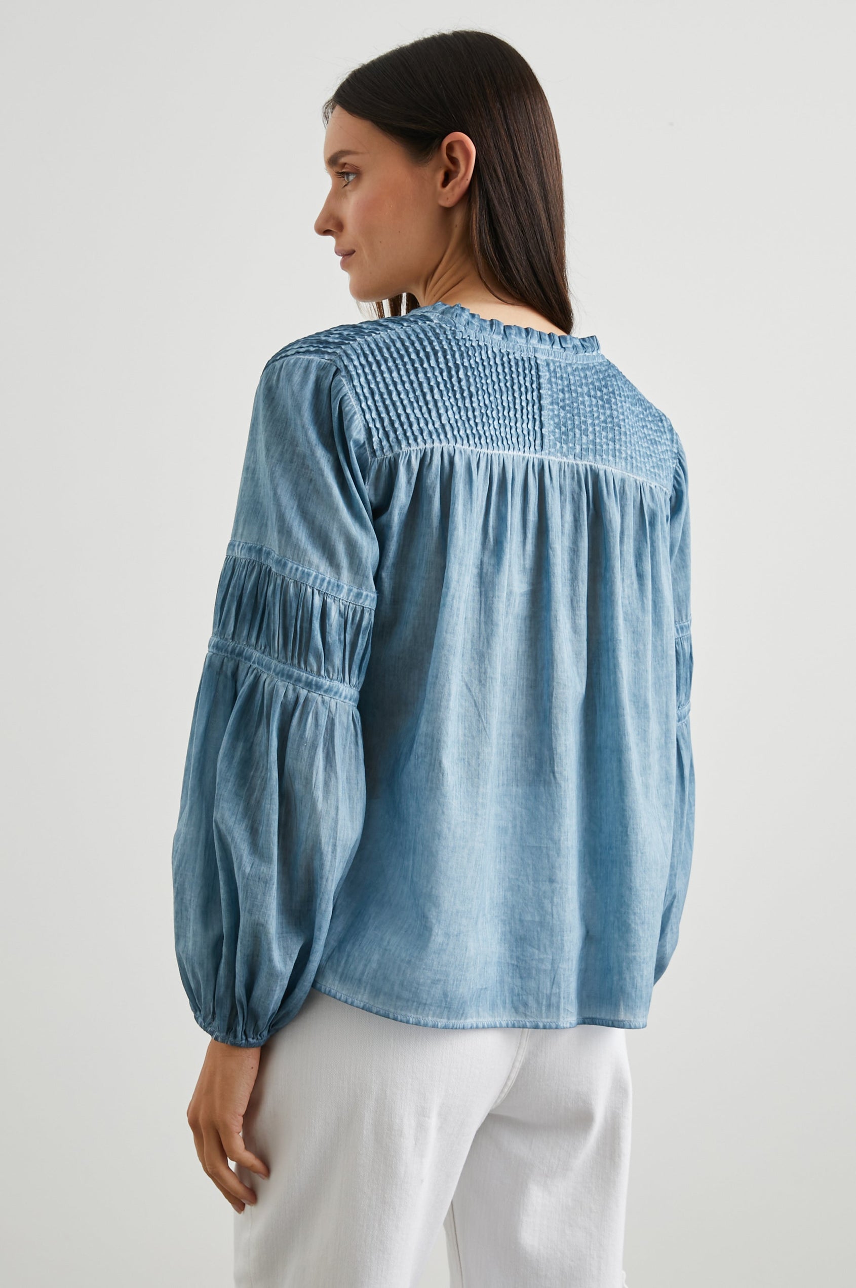 Marli Long-Sleeve Top with a V Neck, Ruffle Collar, Ruching on the Sleeves and Yoke Seam, Tiered Sleeves, and Pleats on the Yoke in Faded Blue Colorway - Back View Featured on Model 