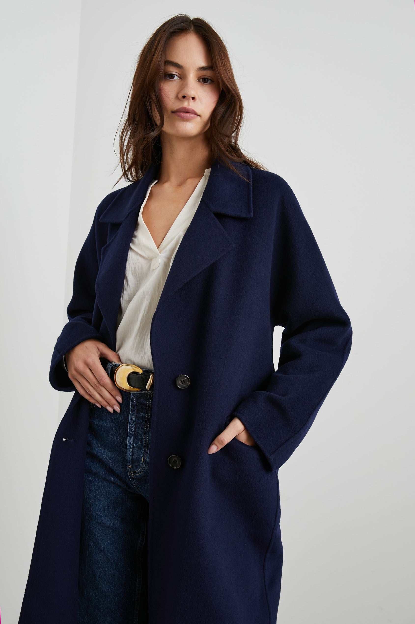 Marta Knee-Length Coat with Two Button Closure, Notched Lapels, Two Front Flap Pockets, and a Tie Belt in Navy Colorway - Front View Featured on Model 