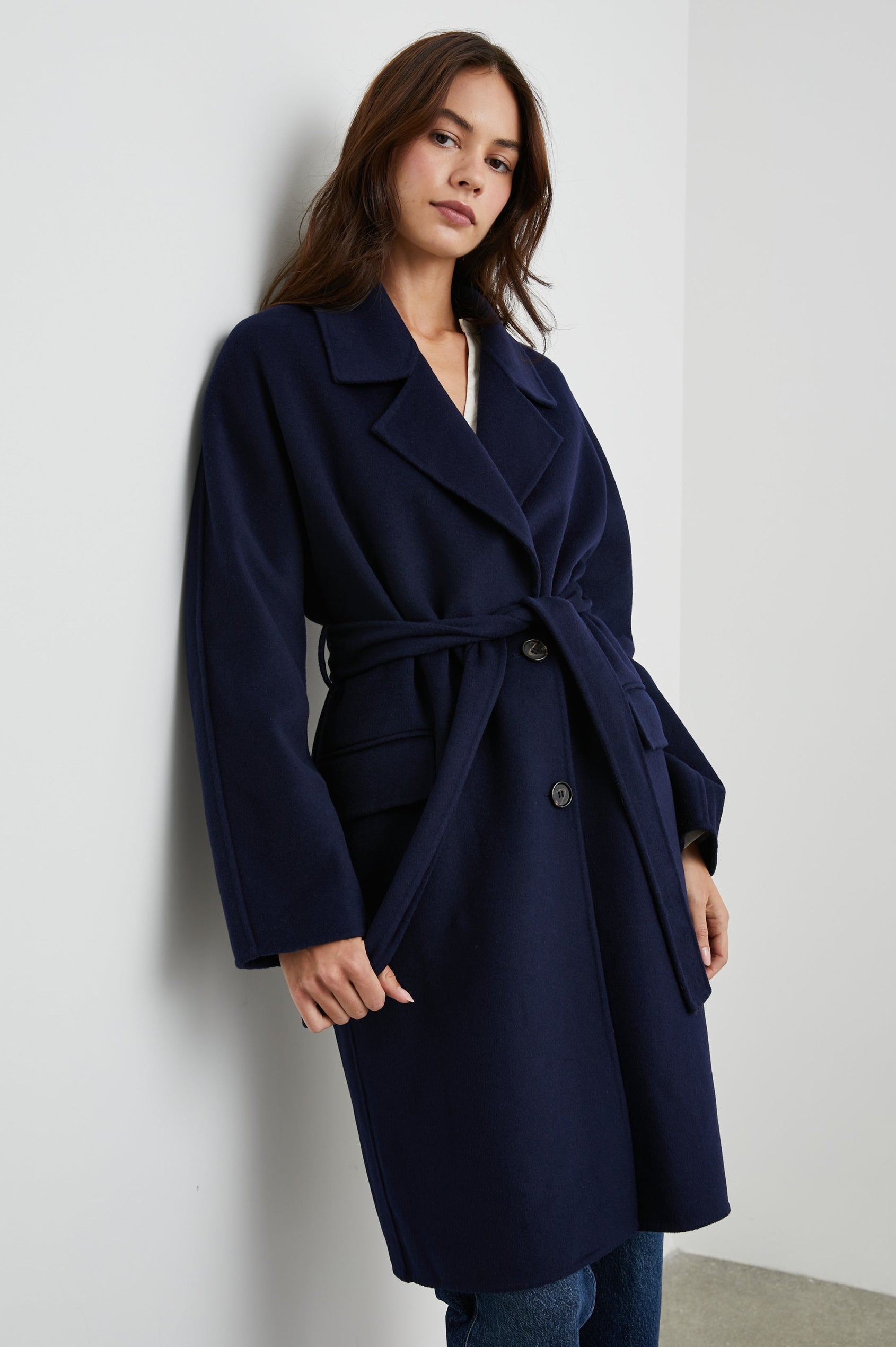 Marta Knee-Length Coat with Two Button Closure, Notched Lapels, Two Front Flap Pockets, and a Tie Belt in Navy Colorway - Front View Featured on Model 