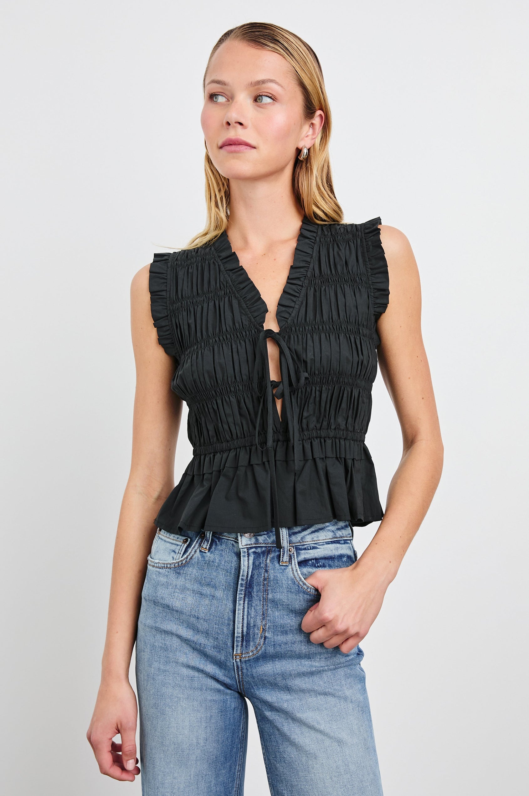 Martine Sleeveless Top with Ruffled Trim, a Deep V-Neck with Ties and Smocking in Black Colorway - Front View Featured on Model 