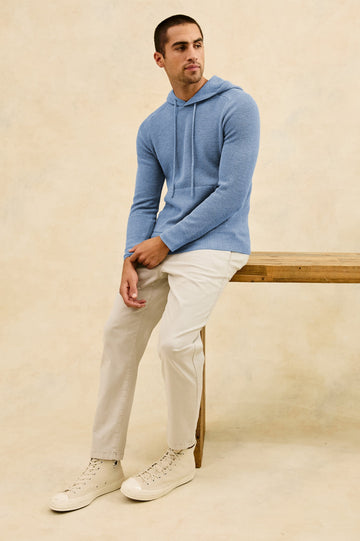 Matador knit sweater with hoodie, adjustable drawstrings, and dual side front pocket in Light Blue Heather - stylized full body view on model, sitting on desk