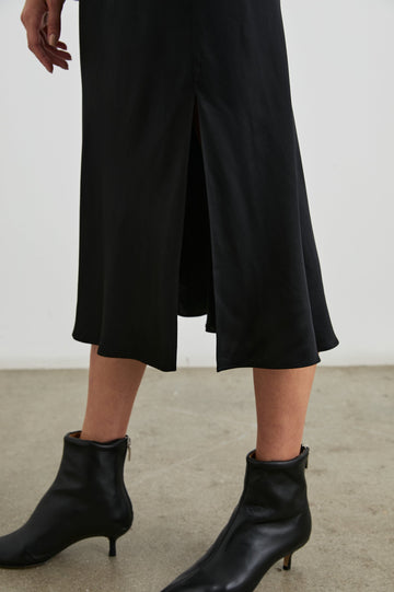 Maya Midi Skirt with Mid-Thigh Side Slit in Black Colorway - Side View Featured on Model