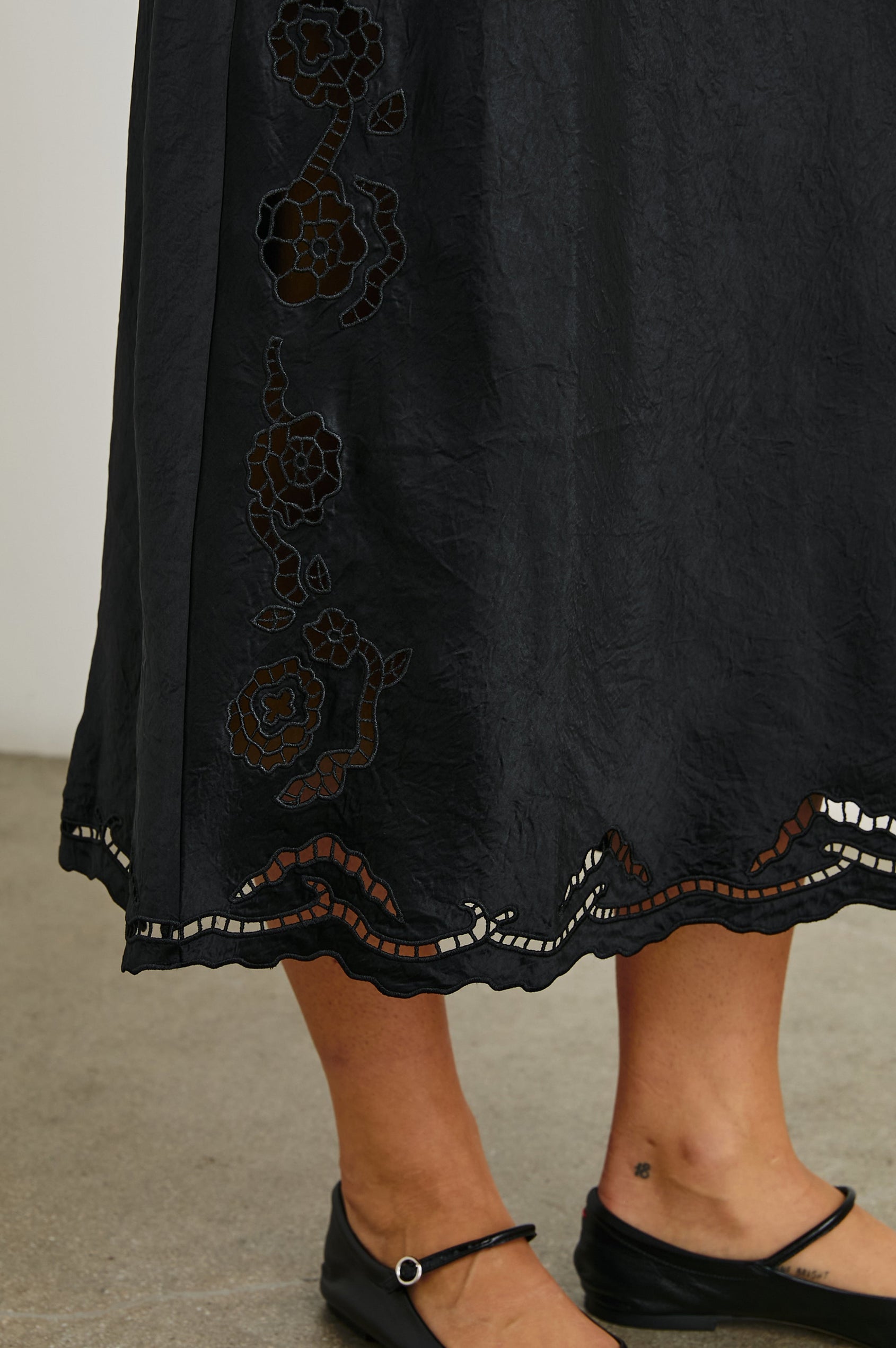 McKenna Short Sleeve Midi Dress with Flutter Sleeves, a Deep V Neck, an Eyelet Design on the Sleeves and Along the Hem and Floral Cutouts on the Skirt Sides in Black Eyelet Colorway  - Front View Featured on Model 