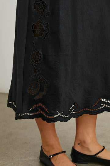 McKenna Short Sleeve Midi Dress with Flutter Sleeves, a Deep V Neck, an Eyelet Design on the Sleeves and Along the Hem and Floral Cutouts on the Skirt Sides in Black Eyelet Colorway  - Front View Featured on Model 