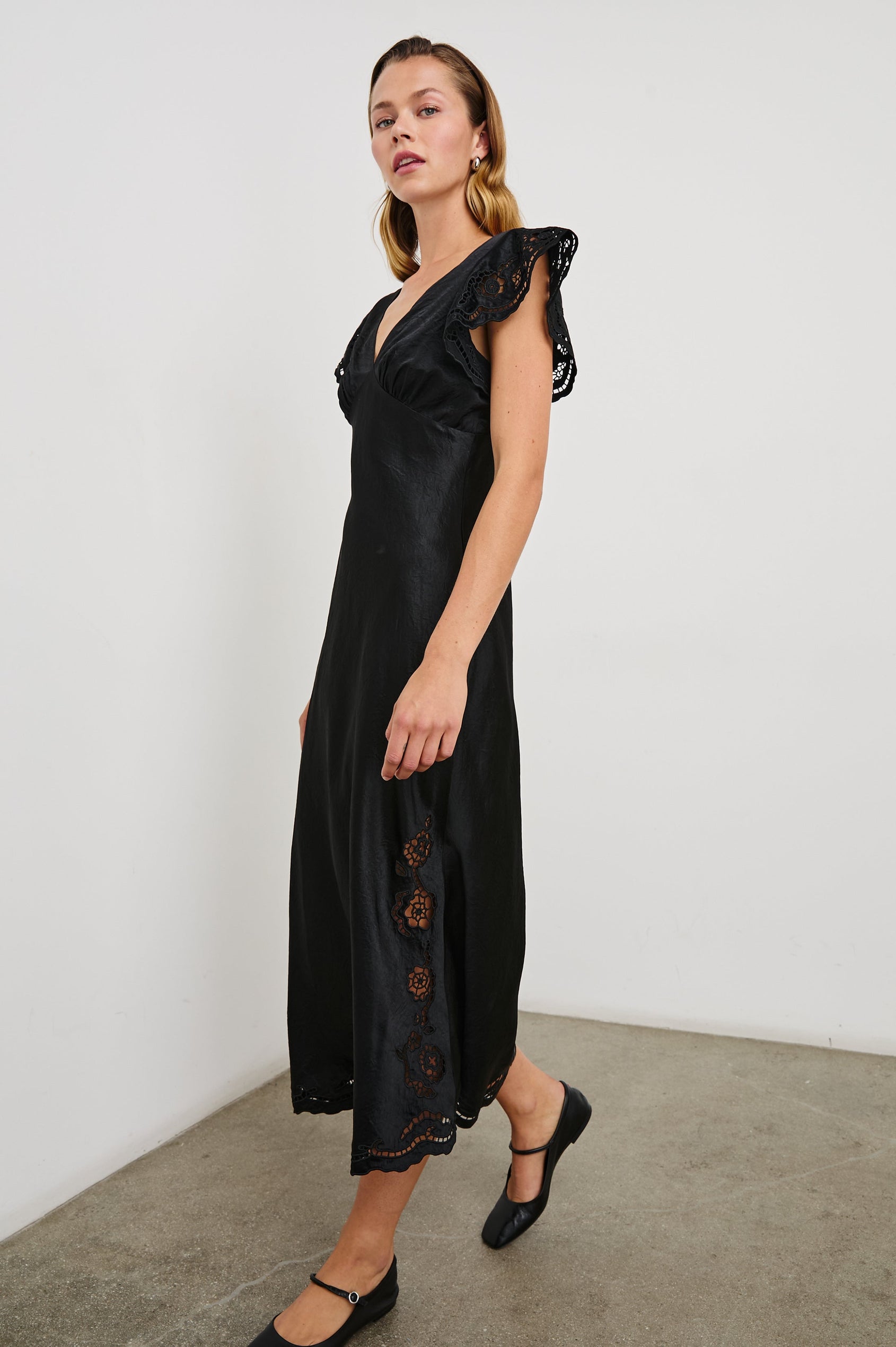 McKenna Short Sleeve Midi Dress with Flutter Sleeves, a Deep V Neck, an Eyelet Design on the Sleeves and Along the Hem and Floral Cutouts on the Skirt Sides in Black Eyelet Colorway  - Front Full Body View Featured on Model 