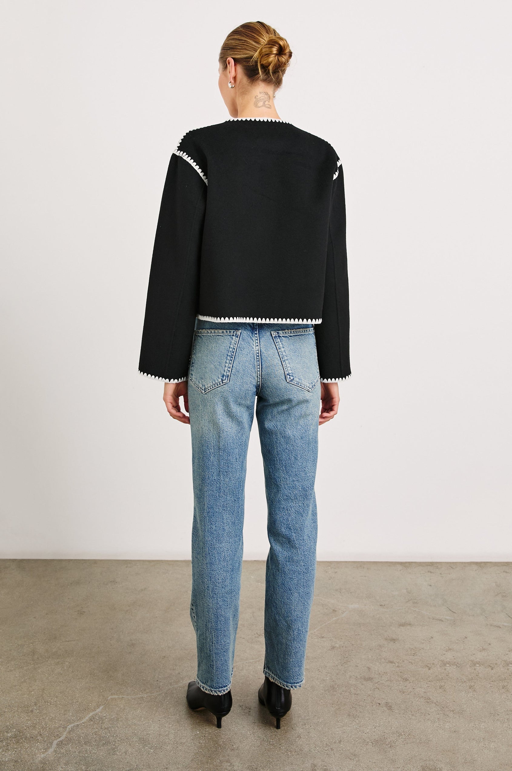 Melanie Jacket with Button Closure and Two Front Patch Pockets in Black Colorway, with White Stitching along the Trim and Pockets - Back Full Body View Featured on Model