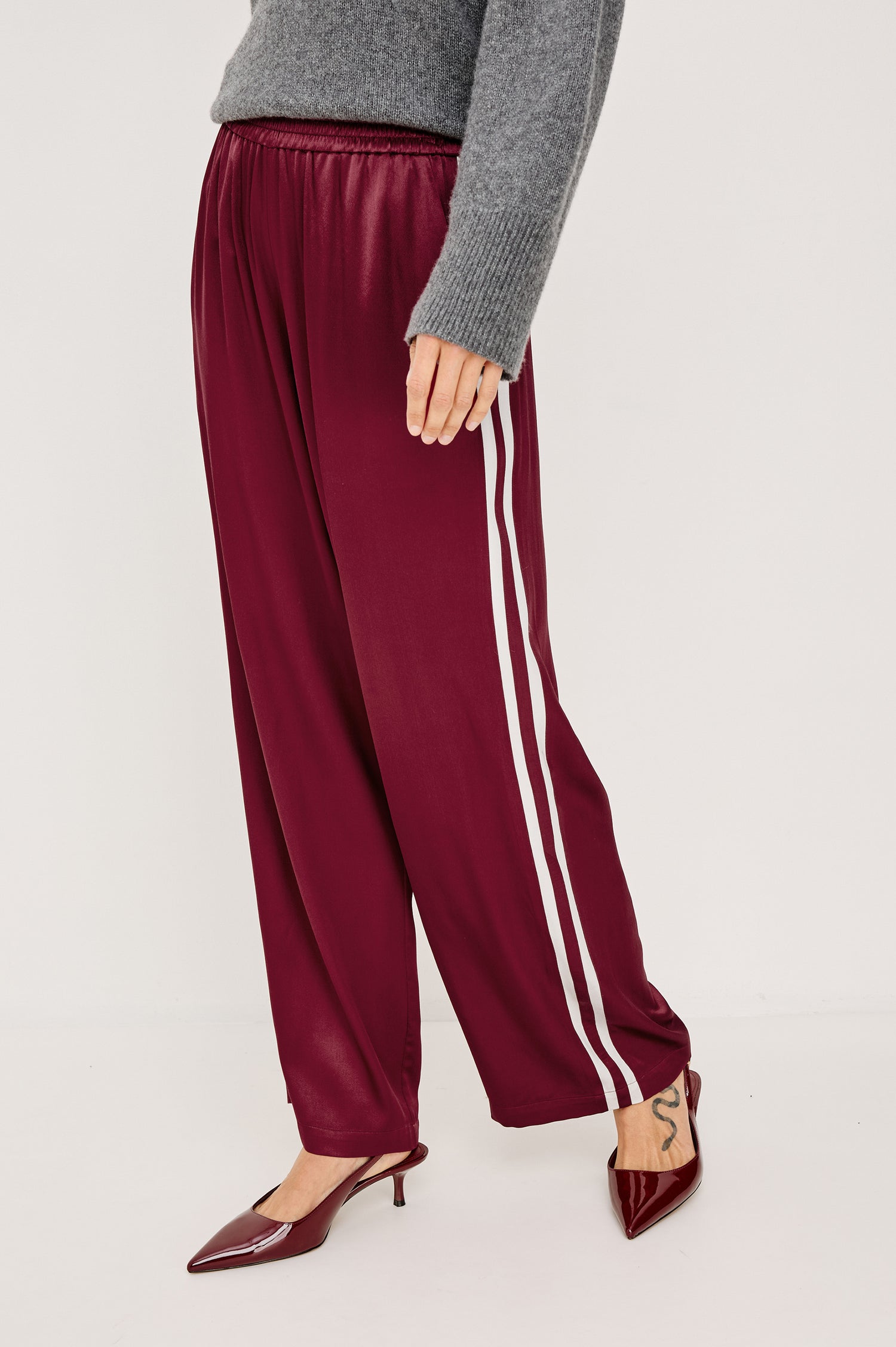 Merida Pant in Satin Back Crepe With Elastic Waistband, Side Pockets, and Wide Legs With Double Side Stripes in Garnet Colorway - Lower Body Side View Featured on Model