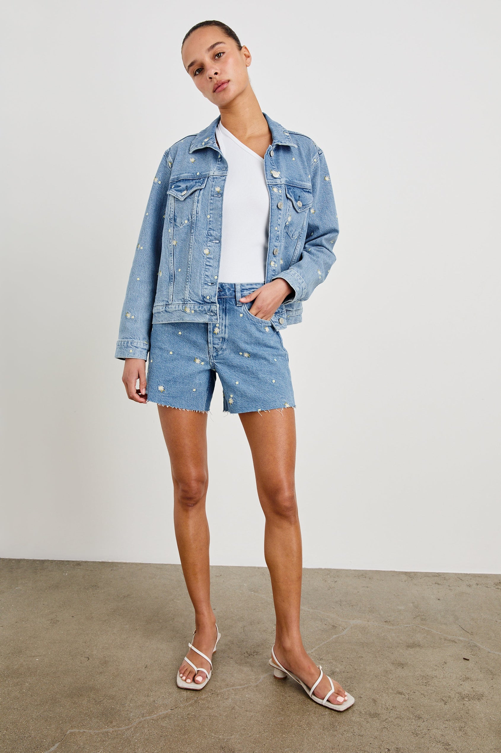 Mesa Indigo Mid Length Short with Pockets and Daisy Embroidery - On Model, full body with matching jacket and hand in pocket.