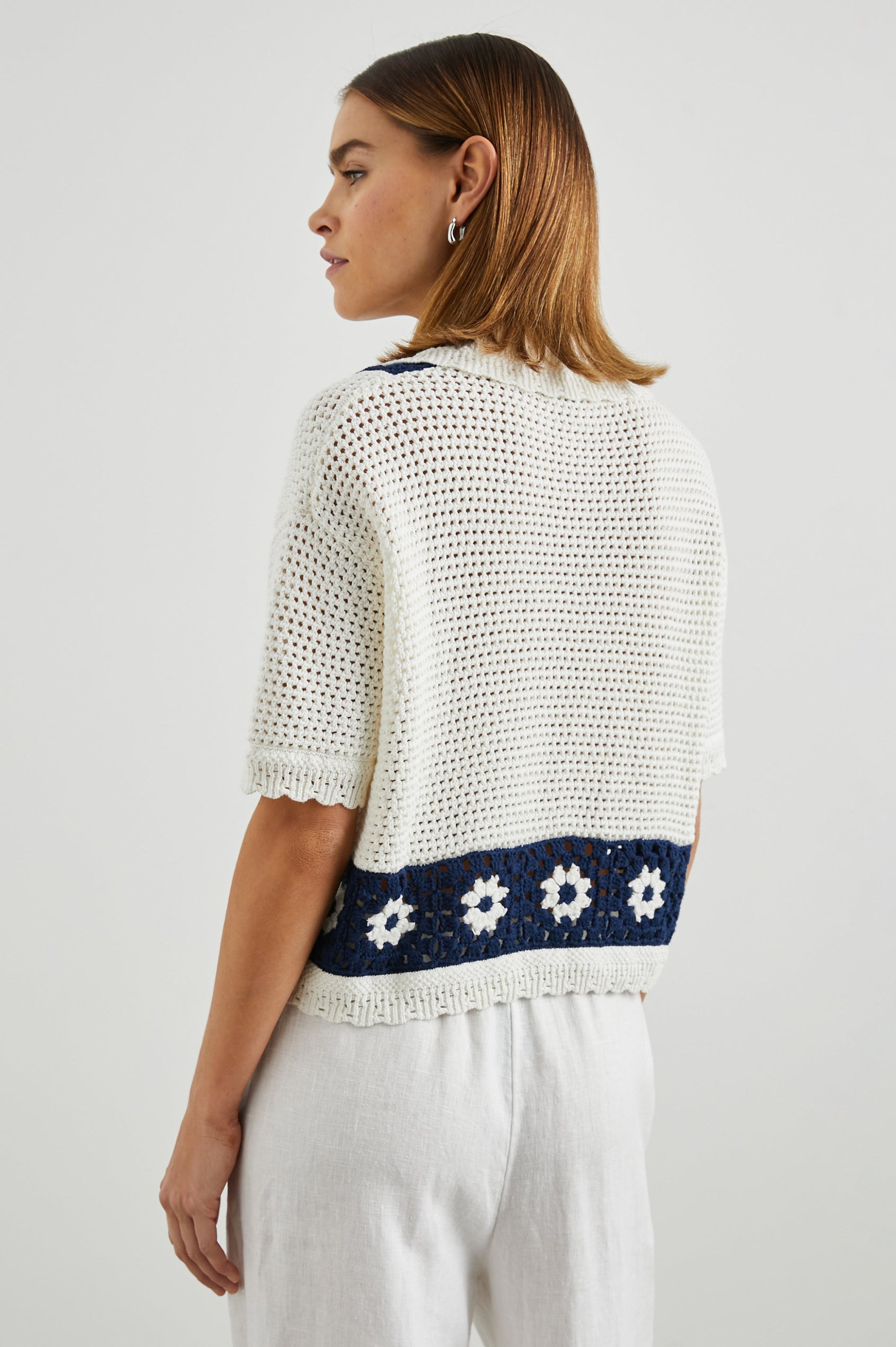 Milan Short-Sleeve Crochet Top with Front Button Closure and a Collar in Navy Crochet Daisies Colorway, White Daisies on a Navy Border on White - Back View Featured on Model 