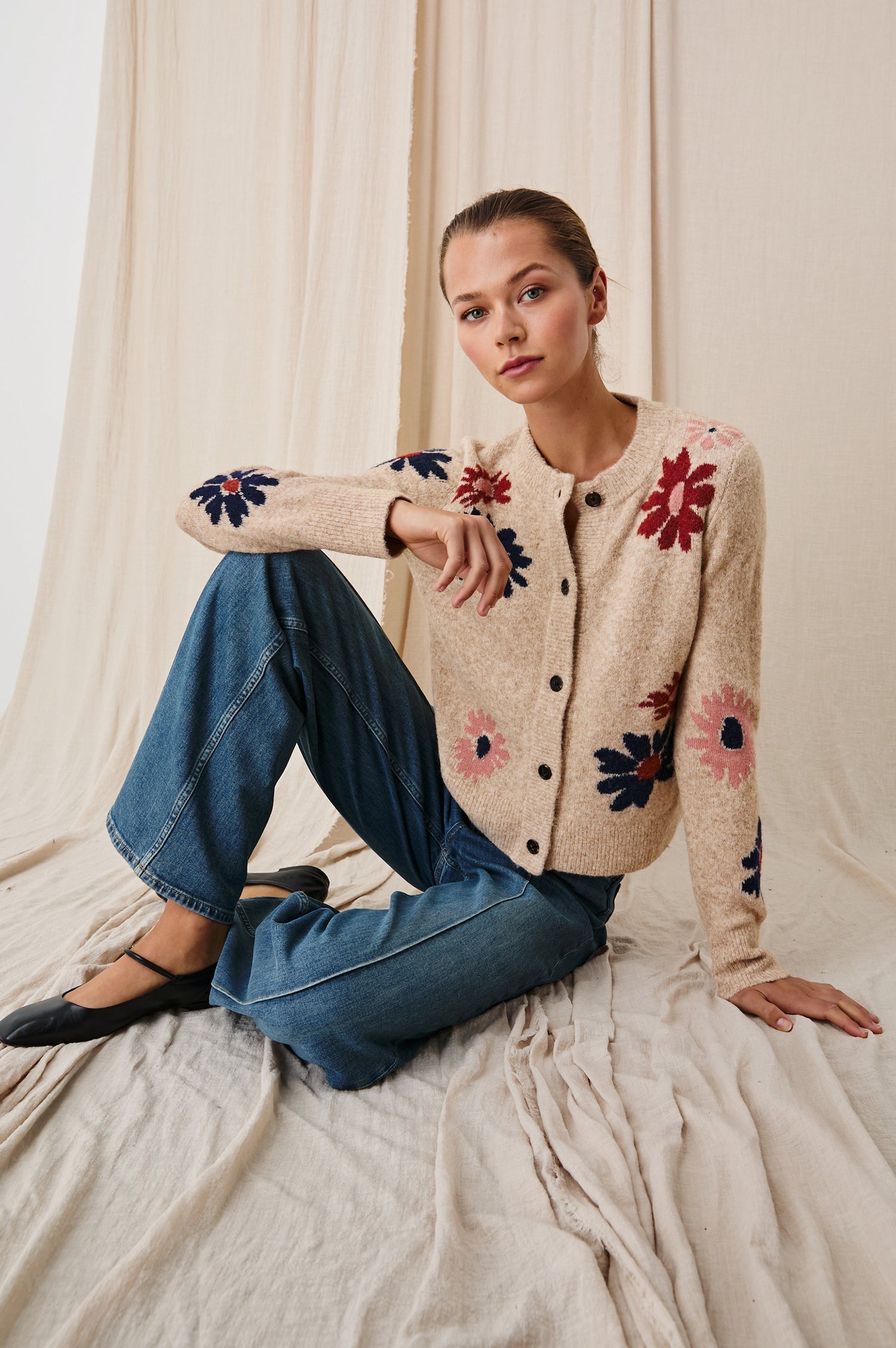 Millie Long-Sleeve Sweater with Front Button Closure, a Crew Neck and Ribbed Trim in Mauve Meadow Colorway, Flowers in Pink, Navy and Red on Oatmeal - Front Full Body View Featured on Seated Model 