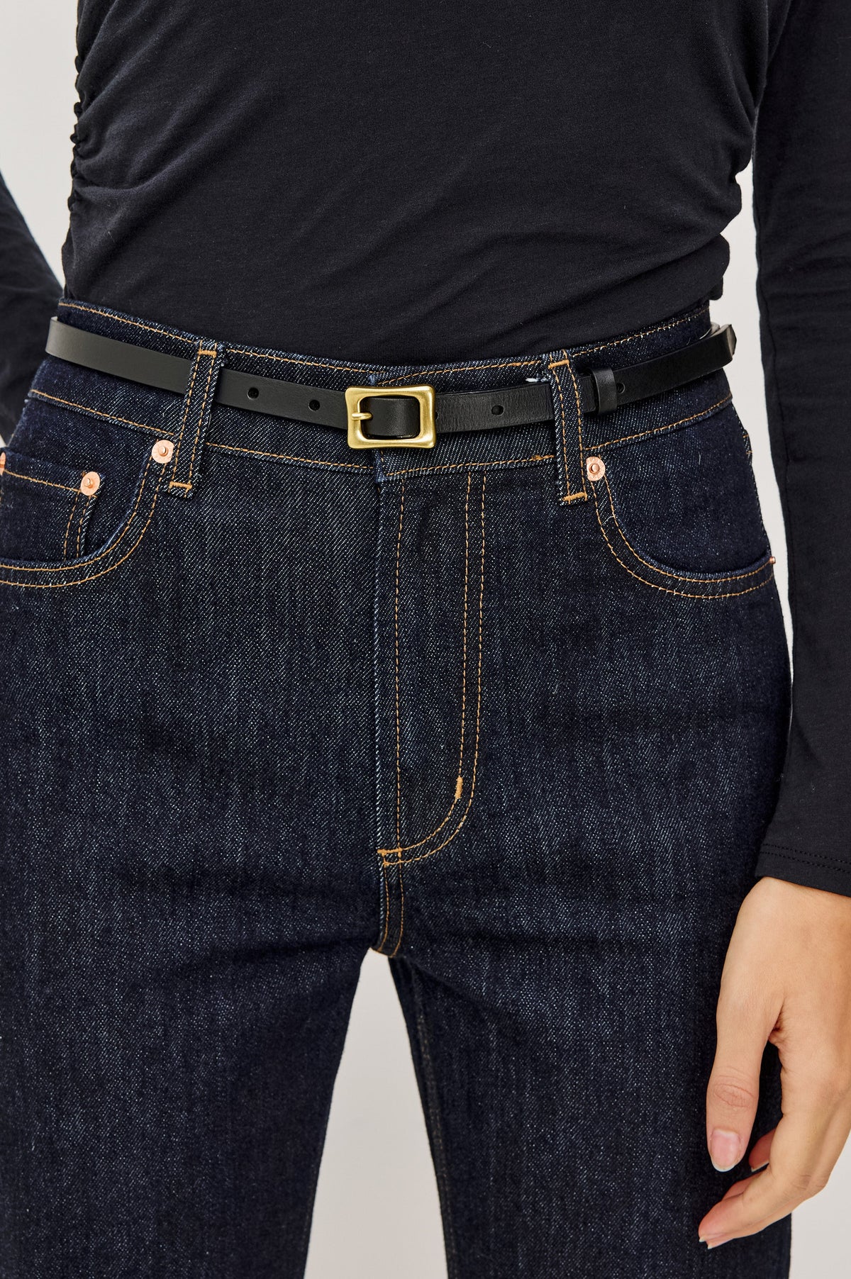 Remi Slim Leather Belt With Adjustable Buckle Closure in Black Gold Colorway - Close Up Front Mid Body View Featured on Model