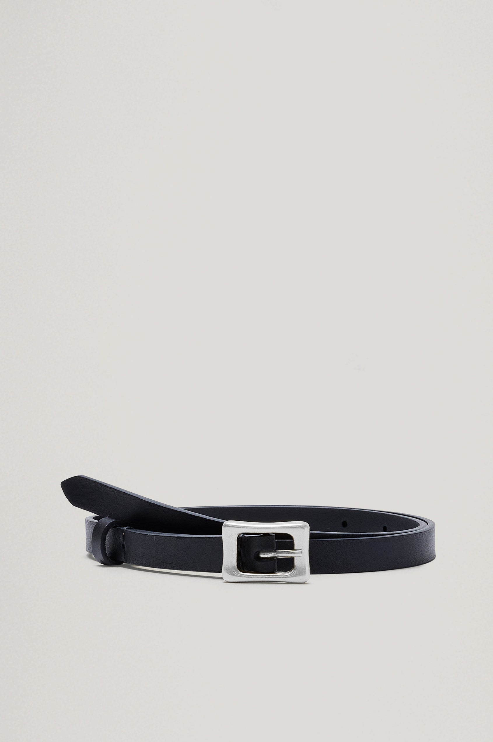 The Remi Belt in Black Leather with a polished silver buckle, buckled and wrapped loosely, front shot.