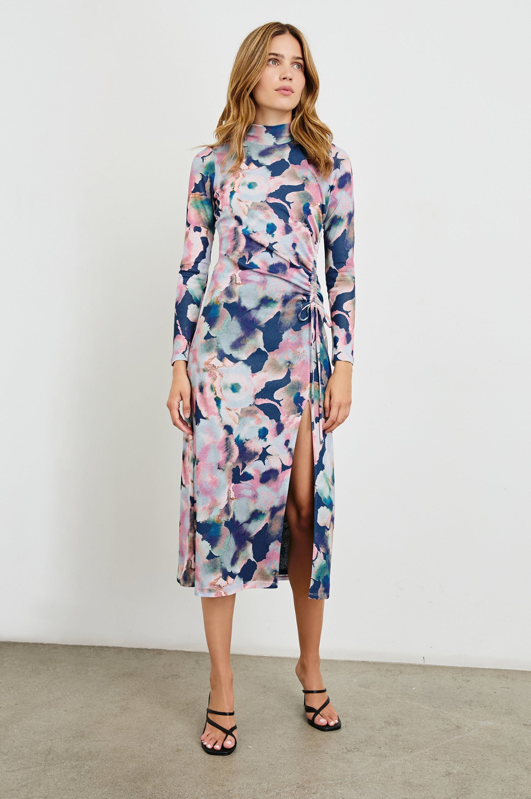 Mona Long Sleeve Midi Dress with a Mock Neck, a Side Slit and Adjustable Ruching along the Left Side with a Drawstring in Midnight Verbena Colorway, Flowers in Pinks, Browns, Greens and Blues on Midnight - Front Full Body View Featured on Model 
