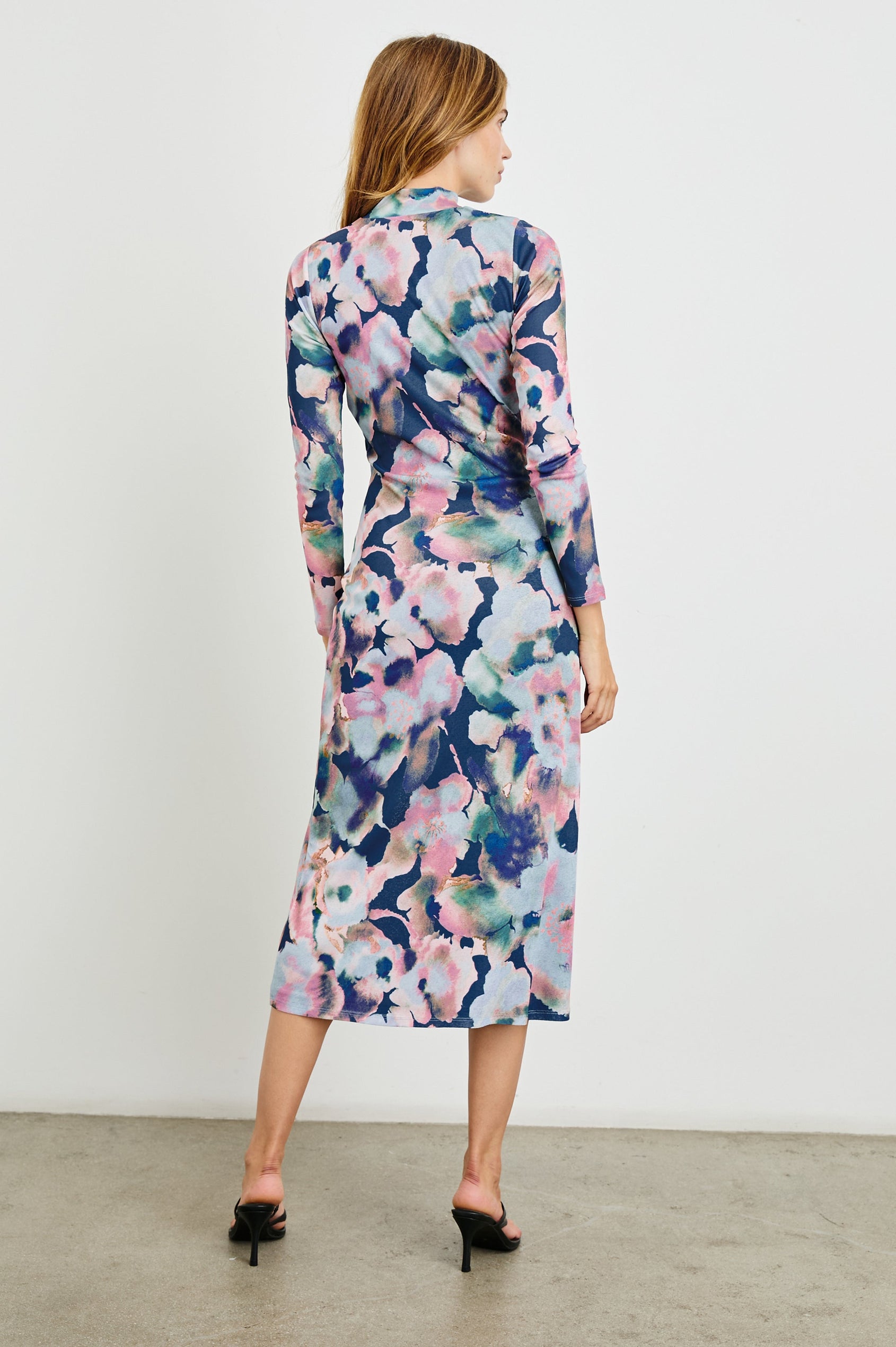 Mona Long Sleeve Midi Dress with a Mock Neck, a Side Slit and Adjustable Ruching along the Left Side with a Drawstring in Midnight Verbena Colorway, Flowers in Pinks, Browns, Greens and Blues on Midnight - Back Full Body View Featured on Model 