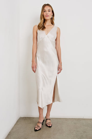 Monique Sleeveless Midi Dress with an Asymmetrical Hem Line, Side Slit, Deep V Neck, and Wide Shoulder Straps in Ivory Colorway - Front Full Body View Featured on Model